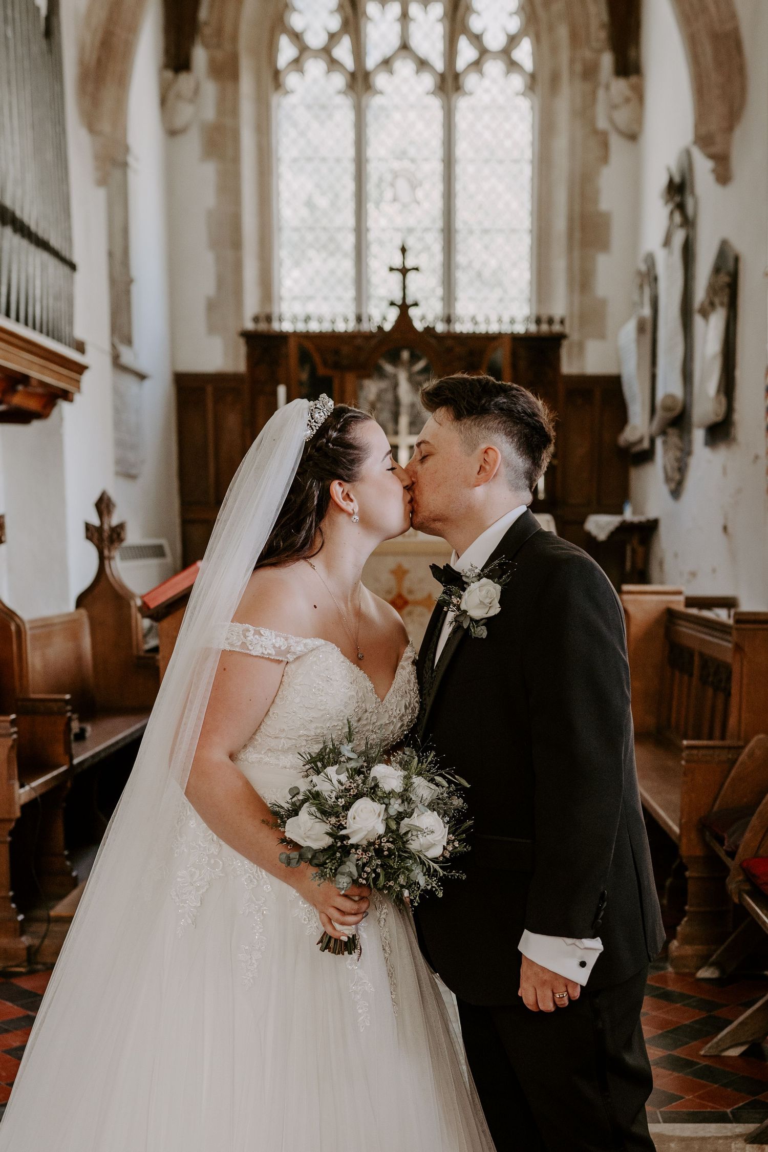 a bride and groom at the alter in a church having their first kiss.