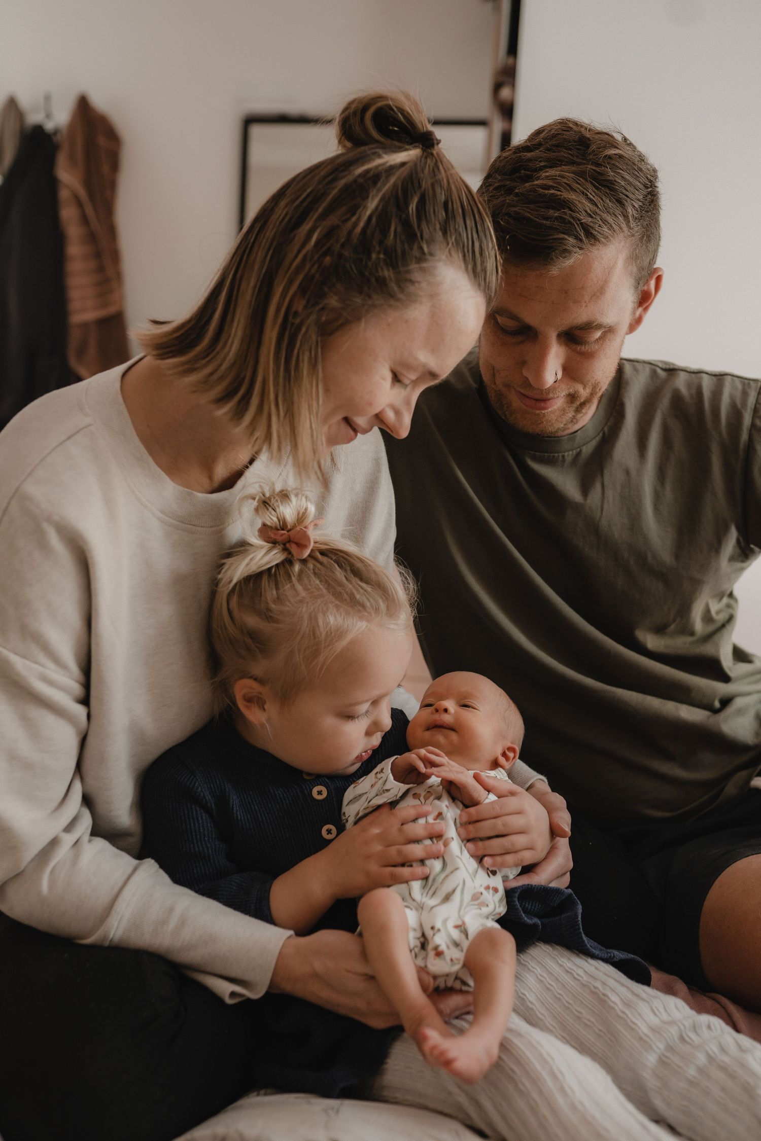 Mother, father, toddler and newborn baby sitting together in their family home