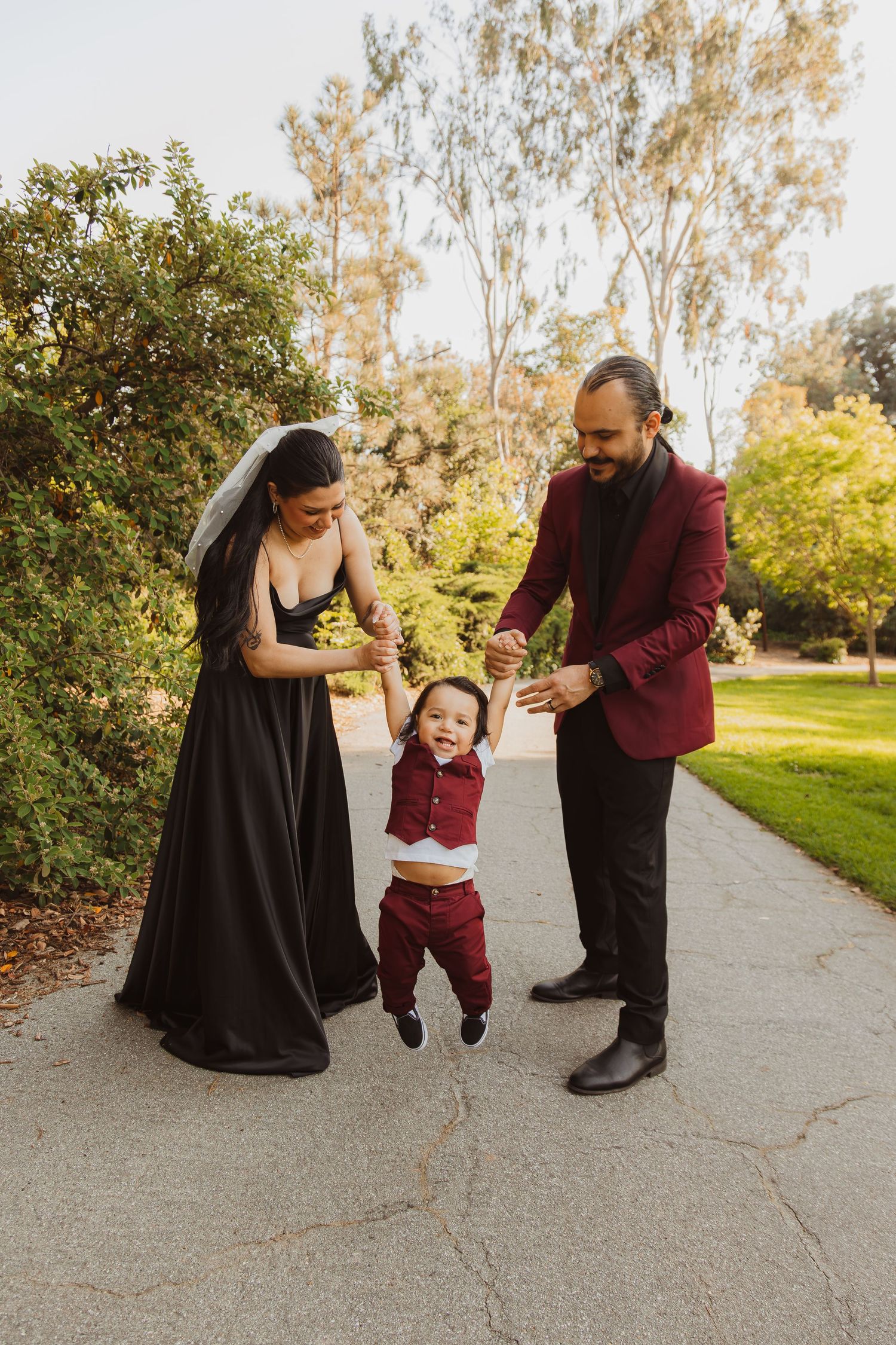 Family moment captured as parents swing child in red outfit between them on pathway.