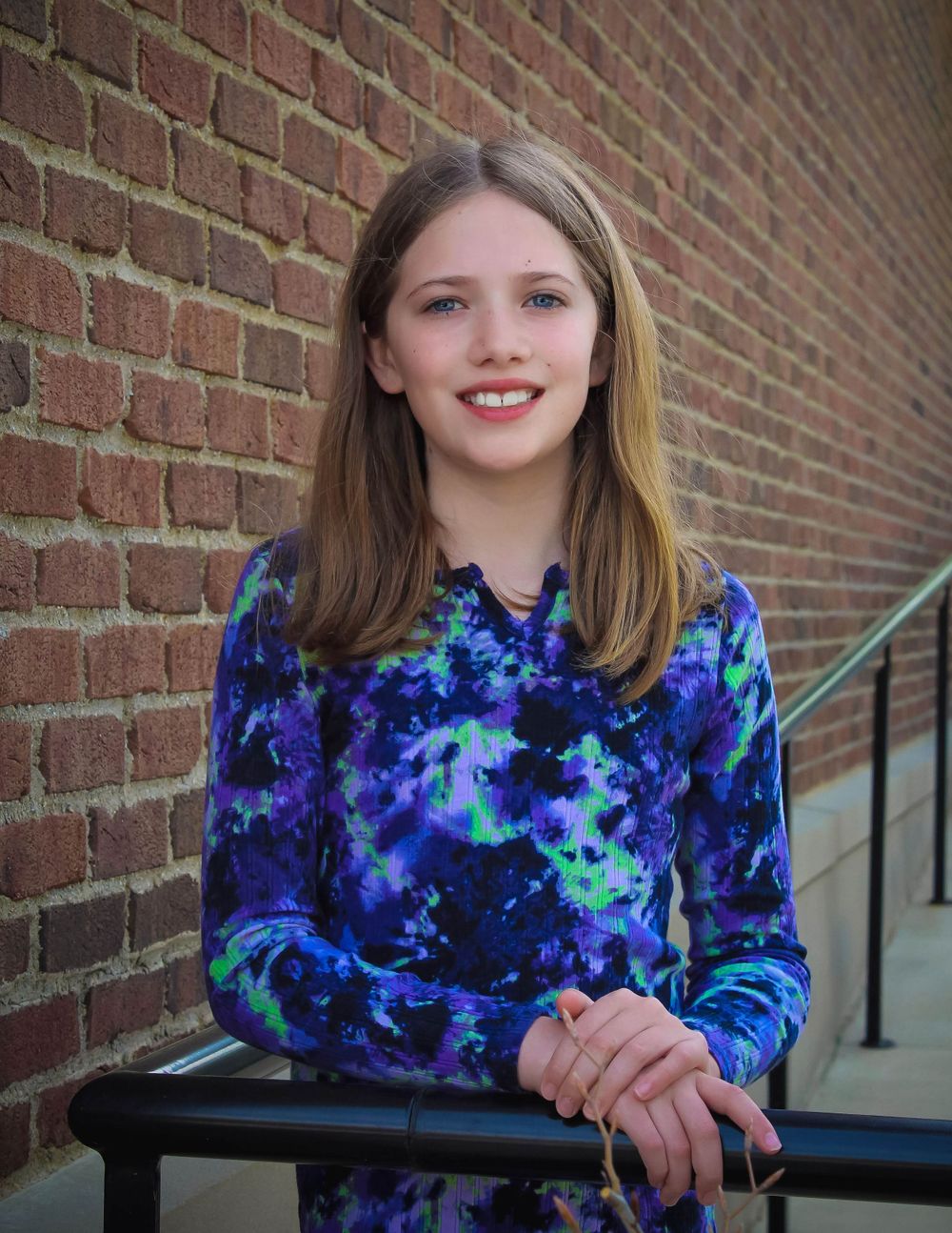 A portrait against red brick wearing a galaxy-print blue dress.