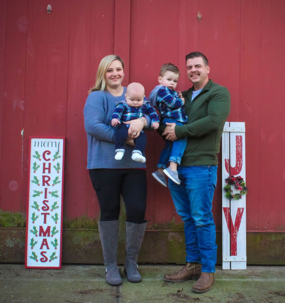 A festive holiday portrait in front of a red barn with Christmas decorations.