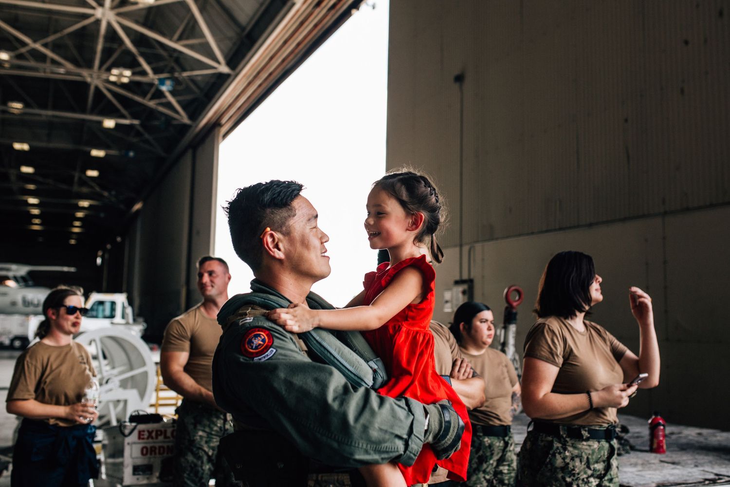 father holding daughter in airfield hanger at military homecoming in norfolk, virginia