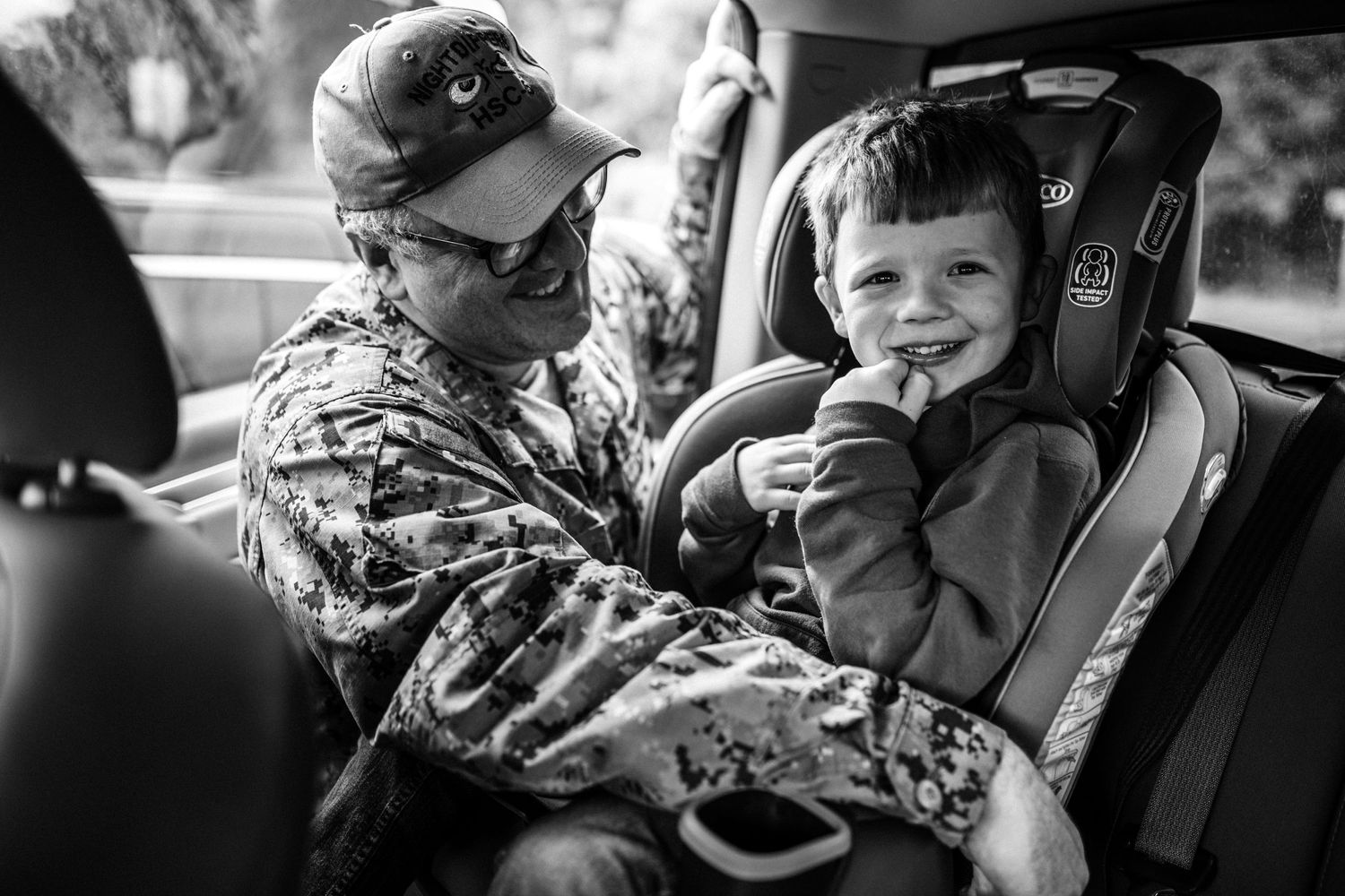 military dad buckling son into car seat after surprise military homecoming in norfolk, virginia