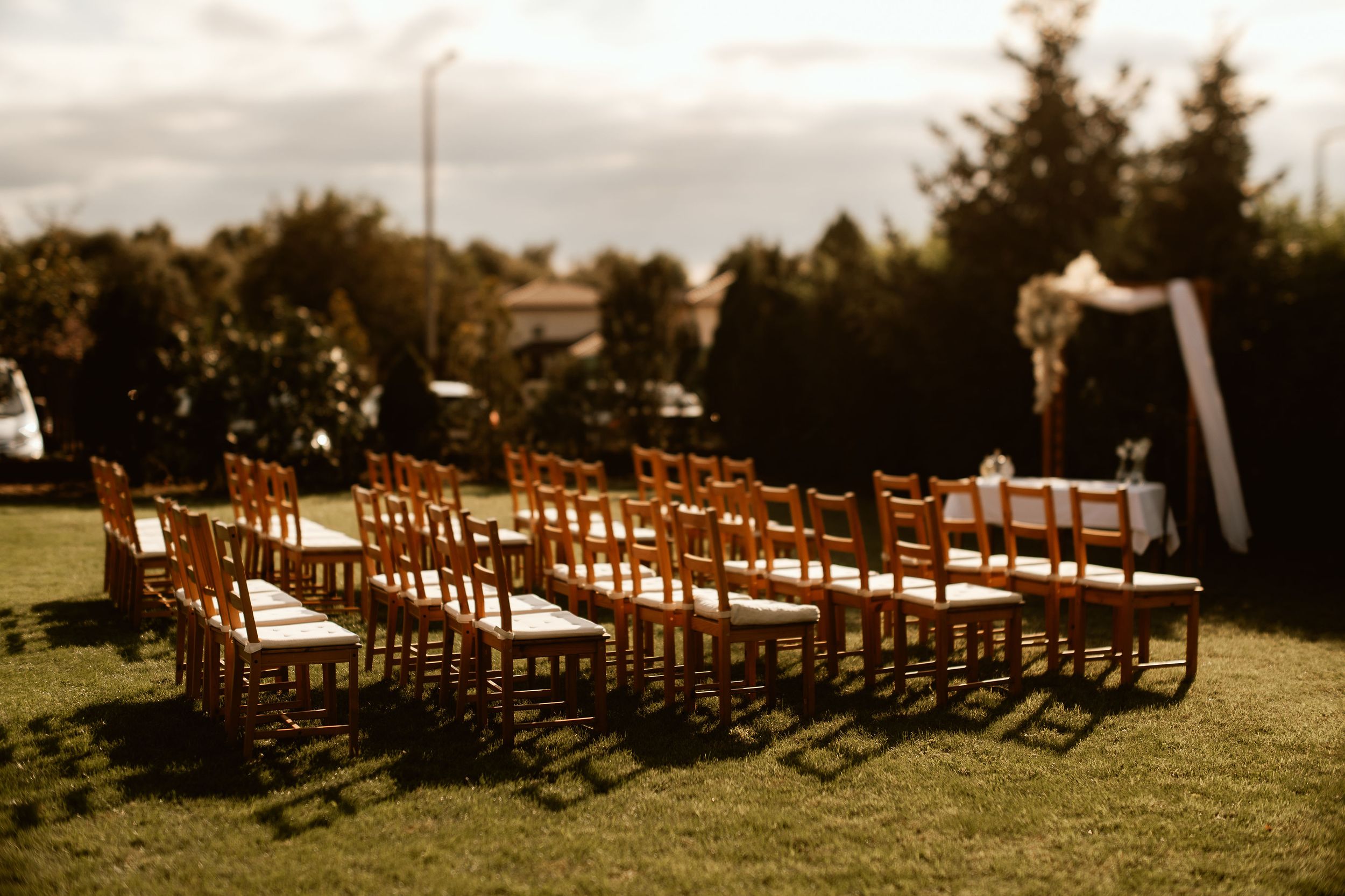 Outdoor wedding ceremony setup with wooden chairs arranged on a grass lawn.