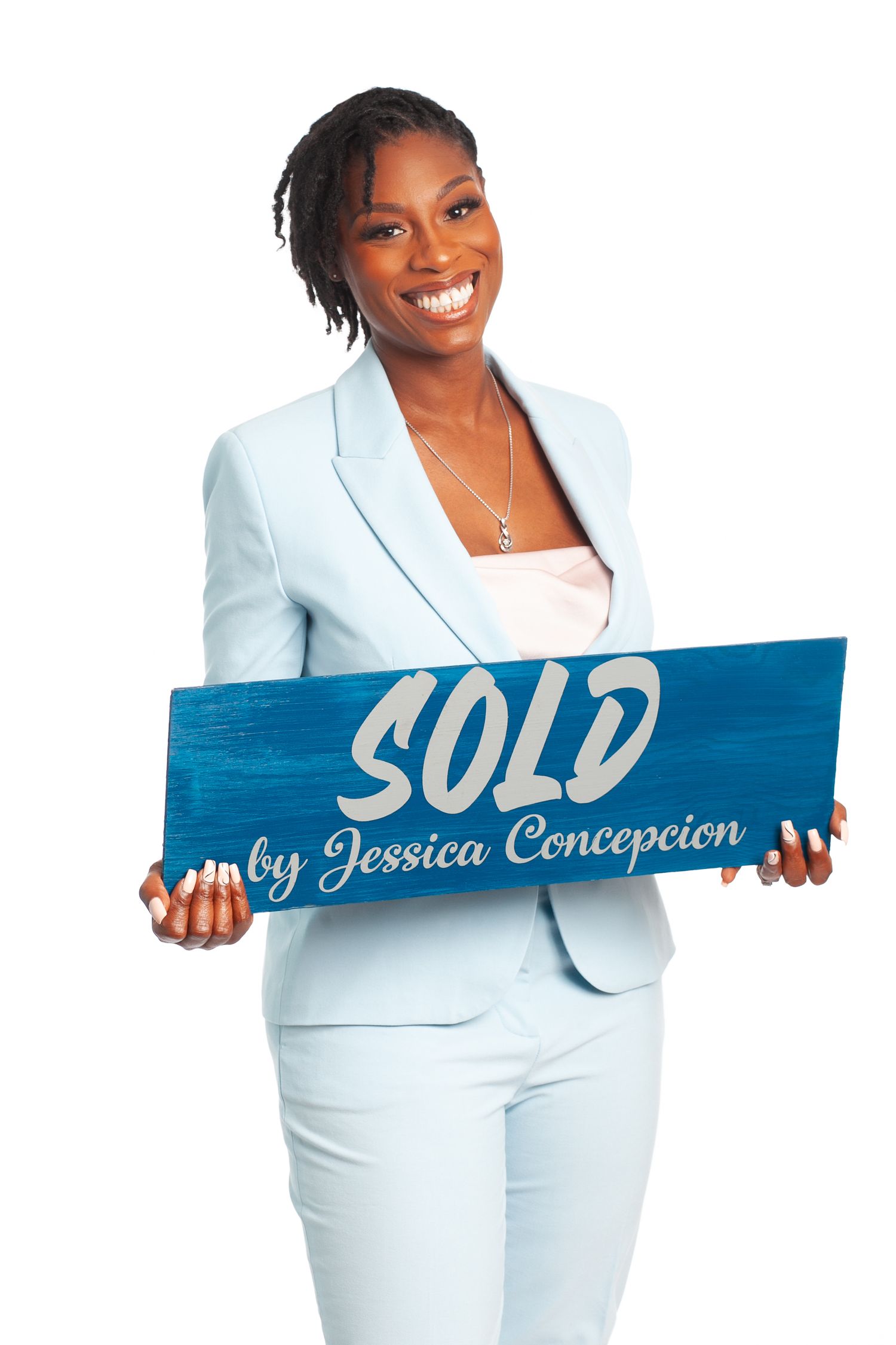 Hampton Roads real estate agent photographed happily in light blue holding a sold sign
