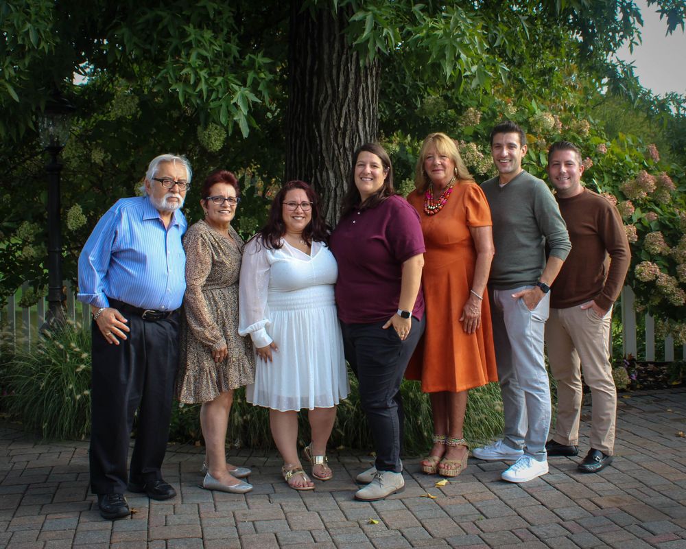Multi-generational family gathering poses together on brick patio.