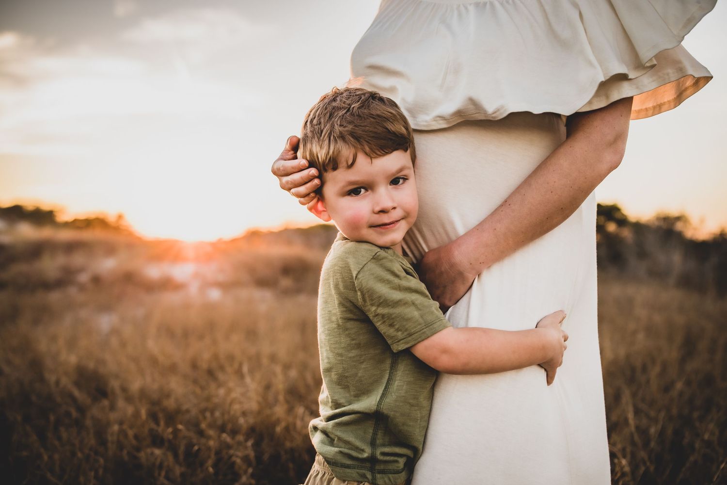 Candid family maternity photos at sunset in outdoor setting.