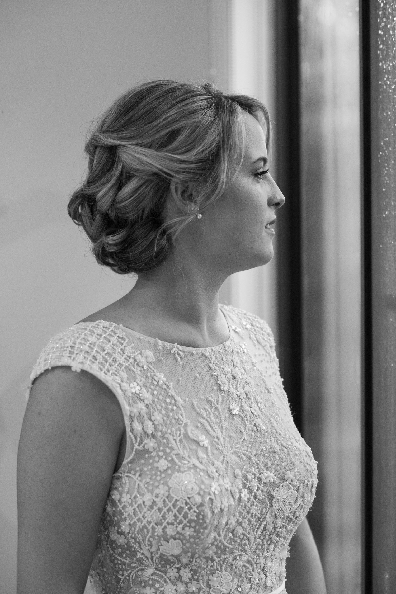 Bride looks out the window before her wedding day. Black & White Wedding Photography