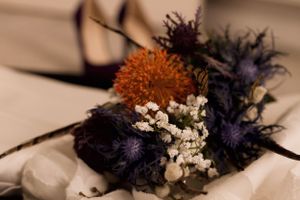 Close-up of a dried floral arrangement with orange and purple blooms and baby's breath.