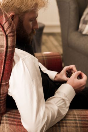 A person in a white shirt and plaid jacket looking down at their hands.