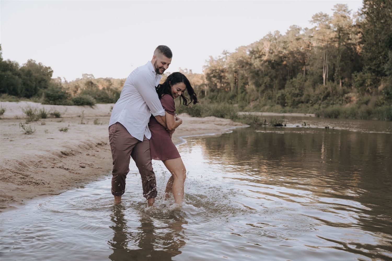 Playful couple splashing in the shallow water at the river's edge.