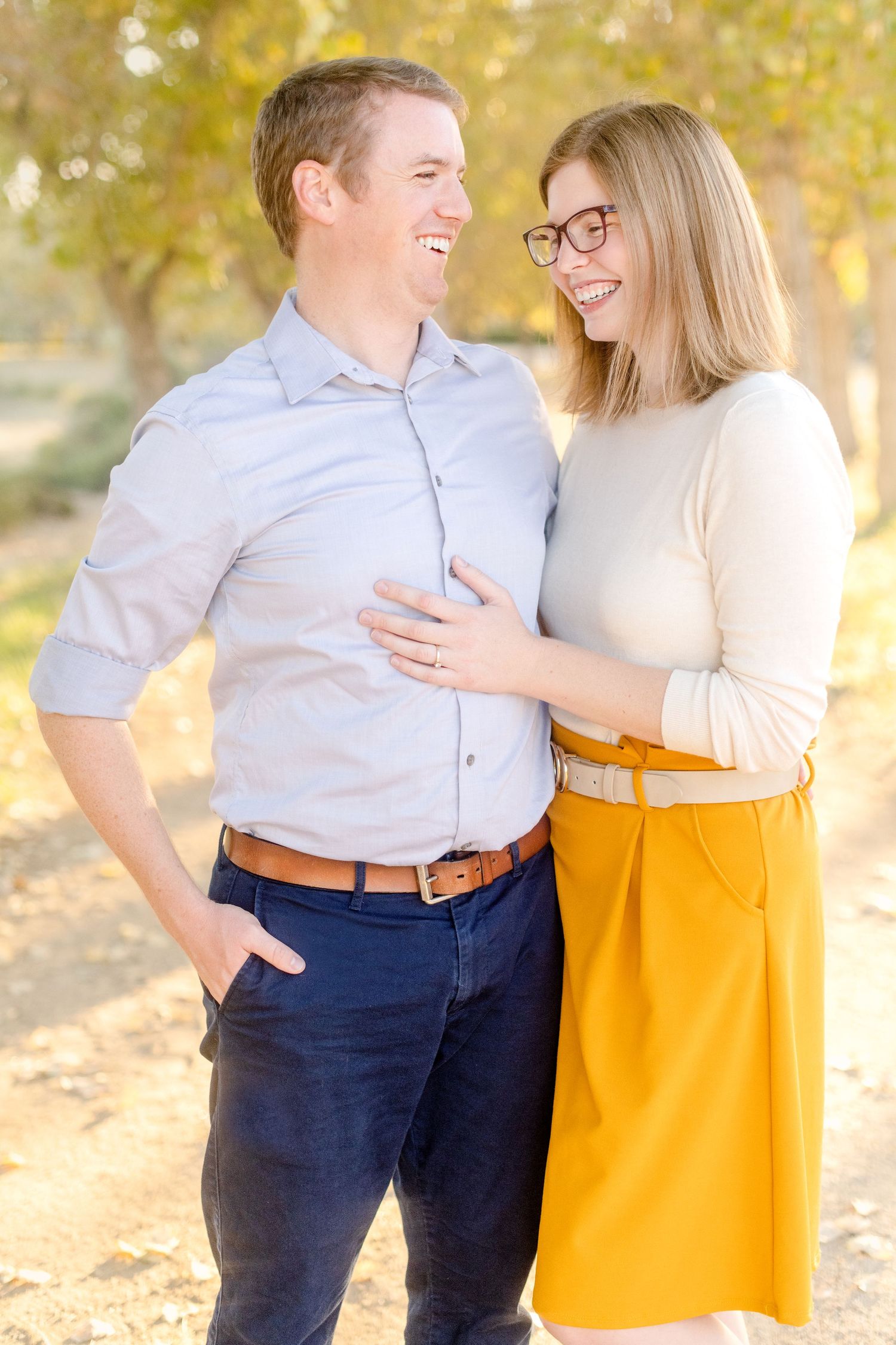 Couple shares a tender moment while standing together outdoors in autumn setting.