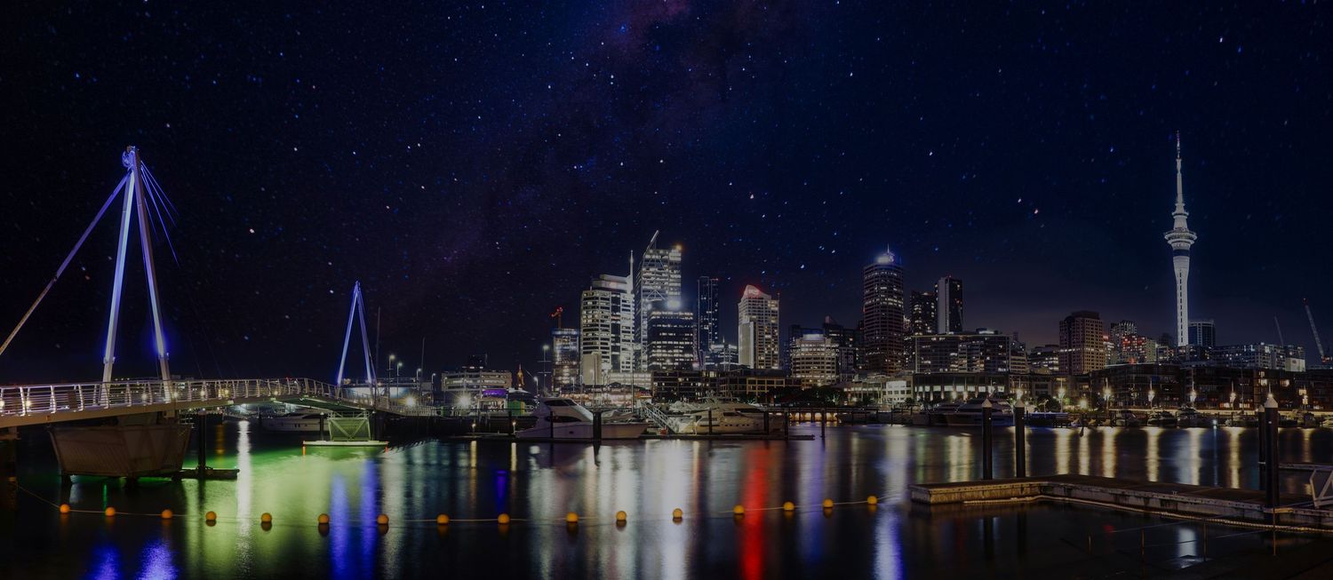 Reflections shimmer as Auckland’s skyline glows beneath a starry sky at the vibrant Viaduct Harbour.