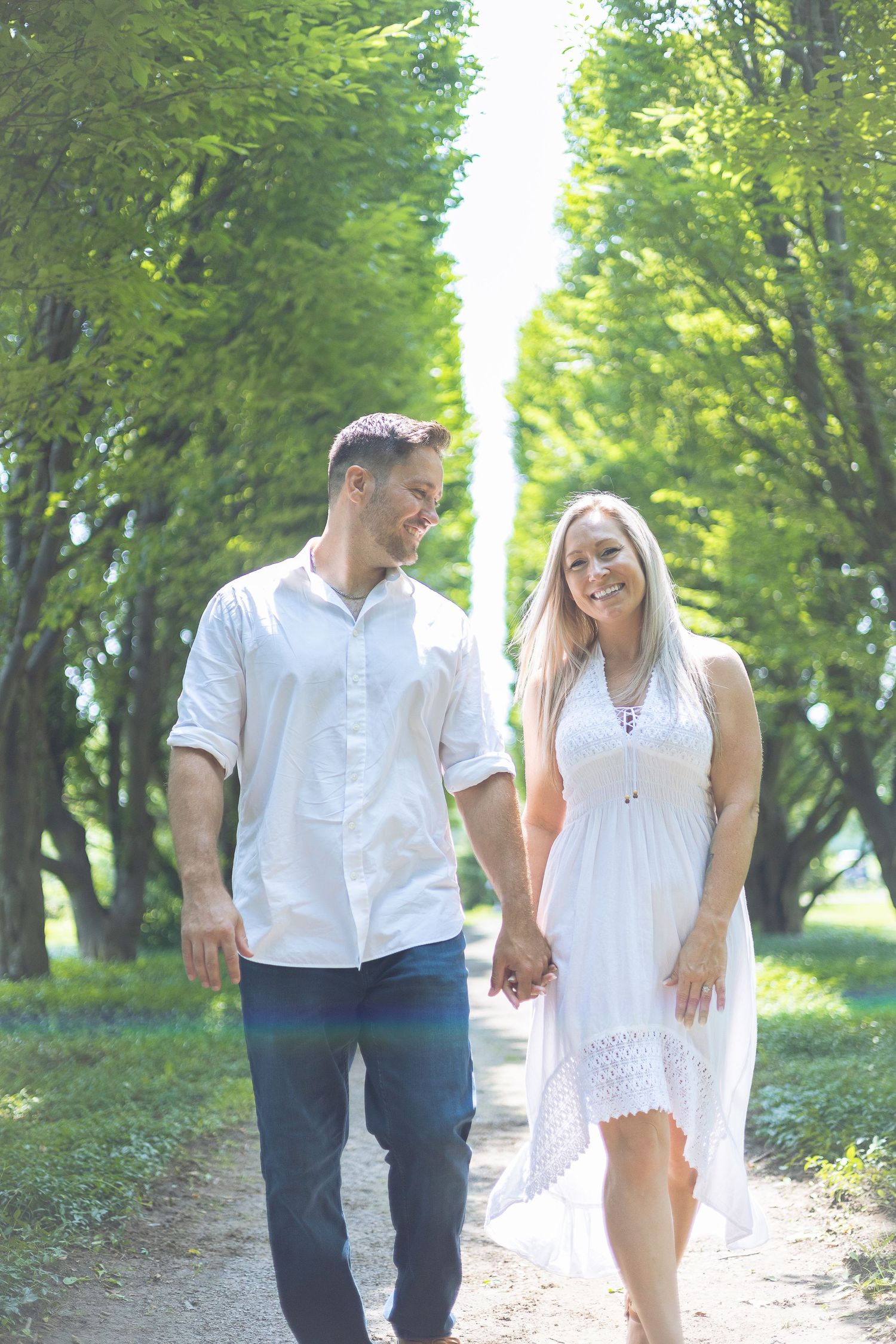 A couple walking down a sun-lit path