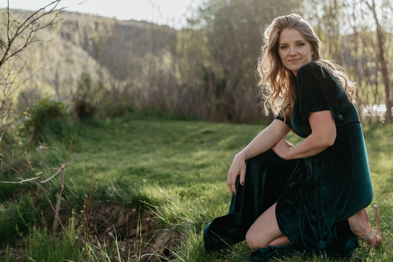 portrait of a woman kneeling on green grass and looking at camera in boise