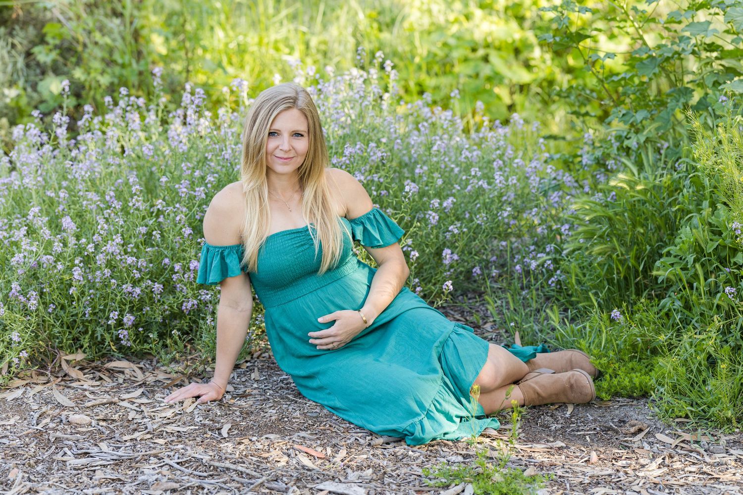 Maternity session sitting on the ground next to flowers in San Clemente