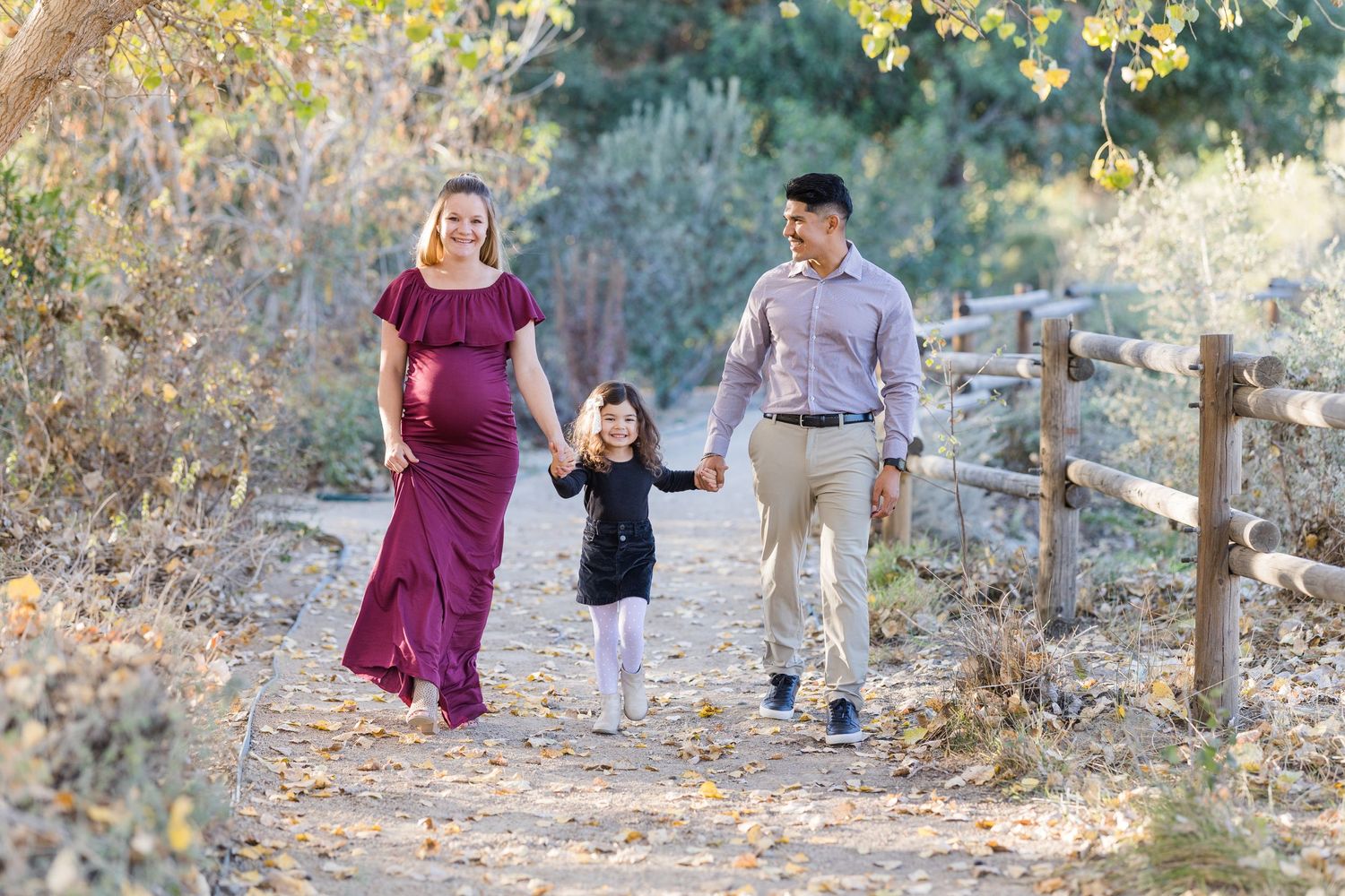 Maternity session with parents and big sister walking on a trail in San Juan Capistrano