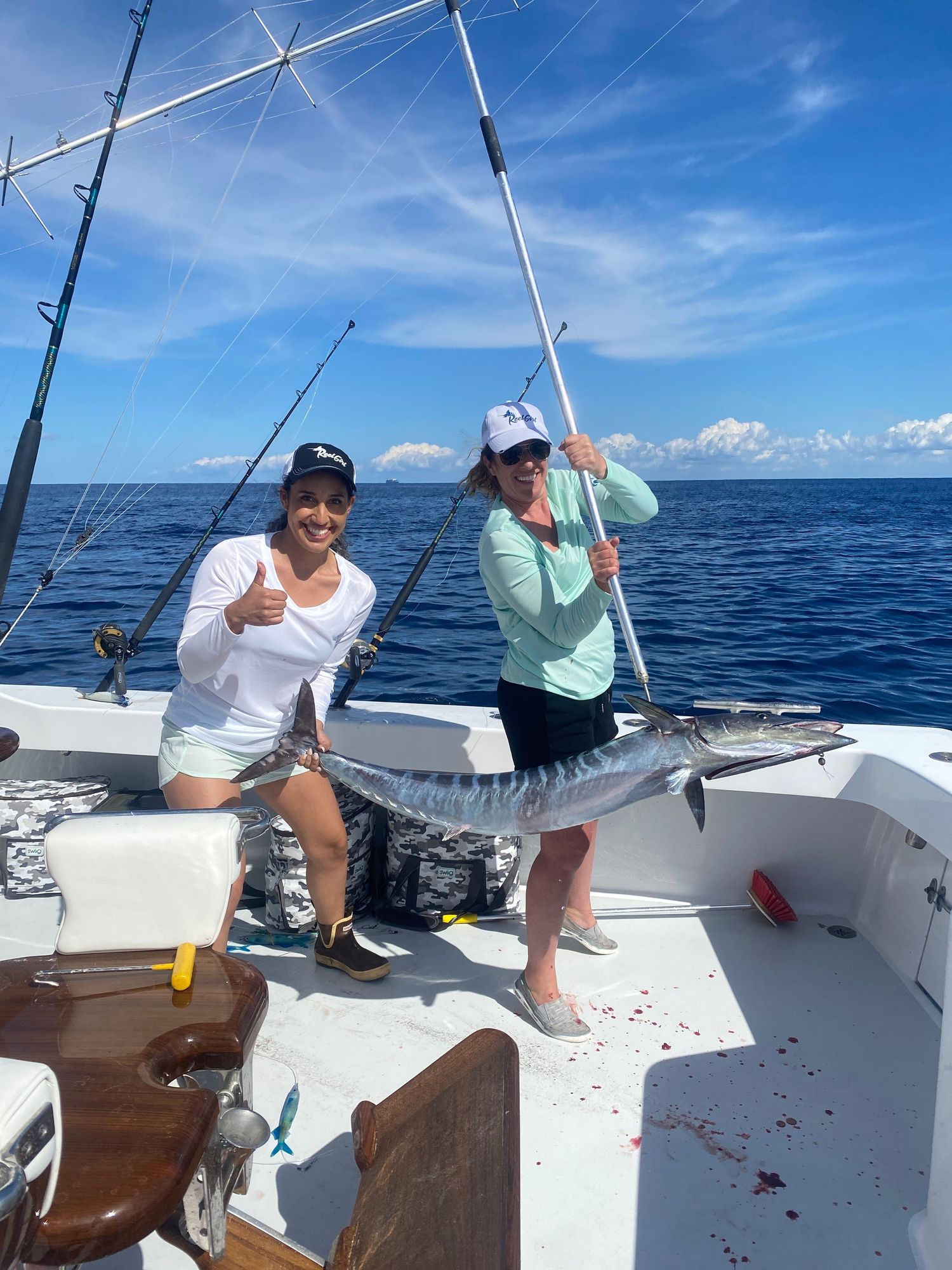 Anglers fishing from white boat deck on bright blue ocean day.