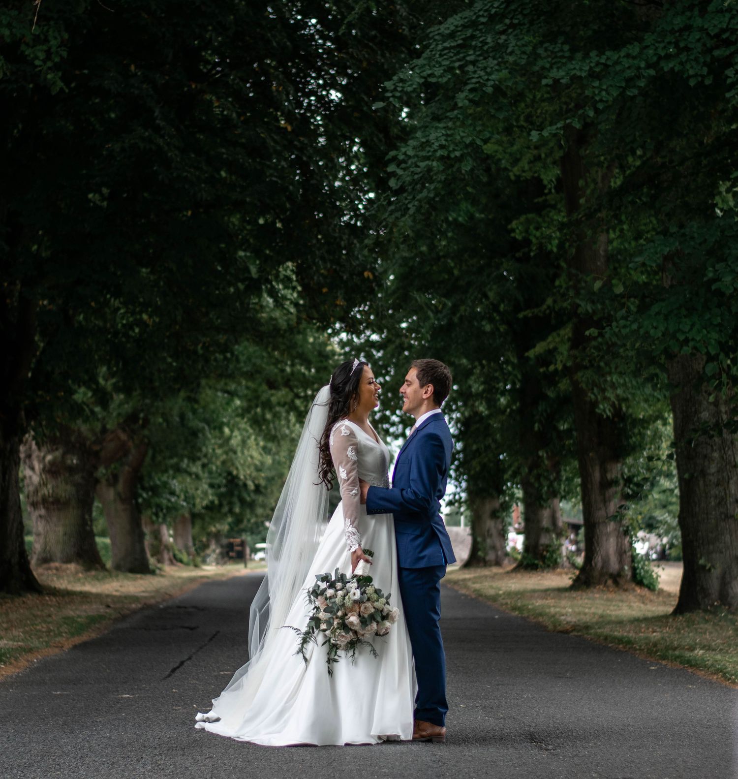 Elegant wedding photography session along a tree-lined pathway.