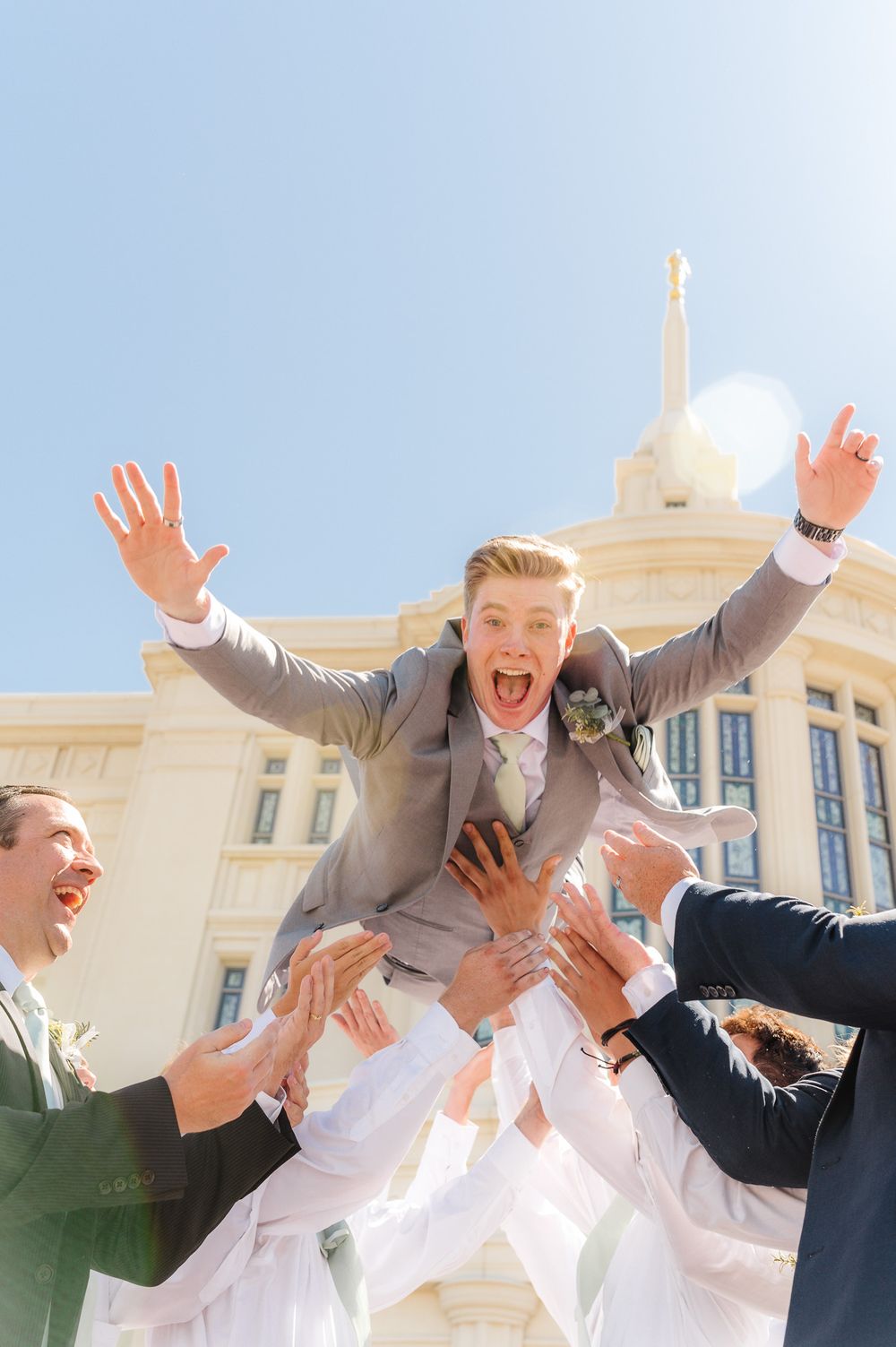 Joyful wedding celebration with people jumping and cheering outside.