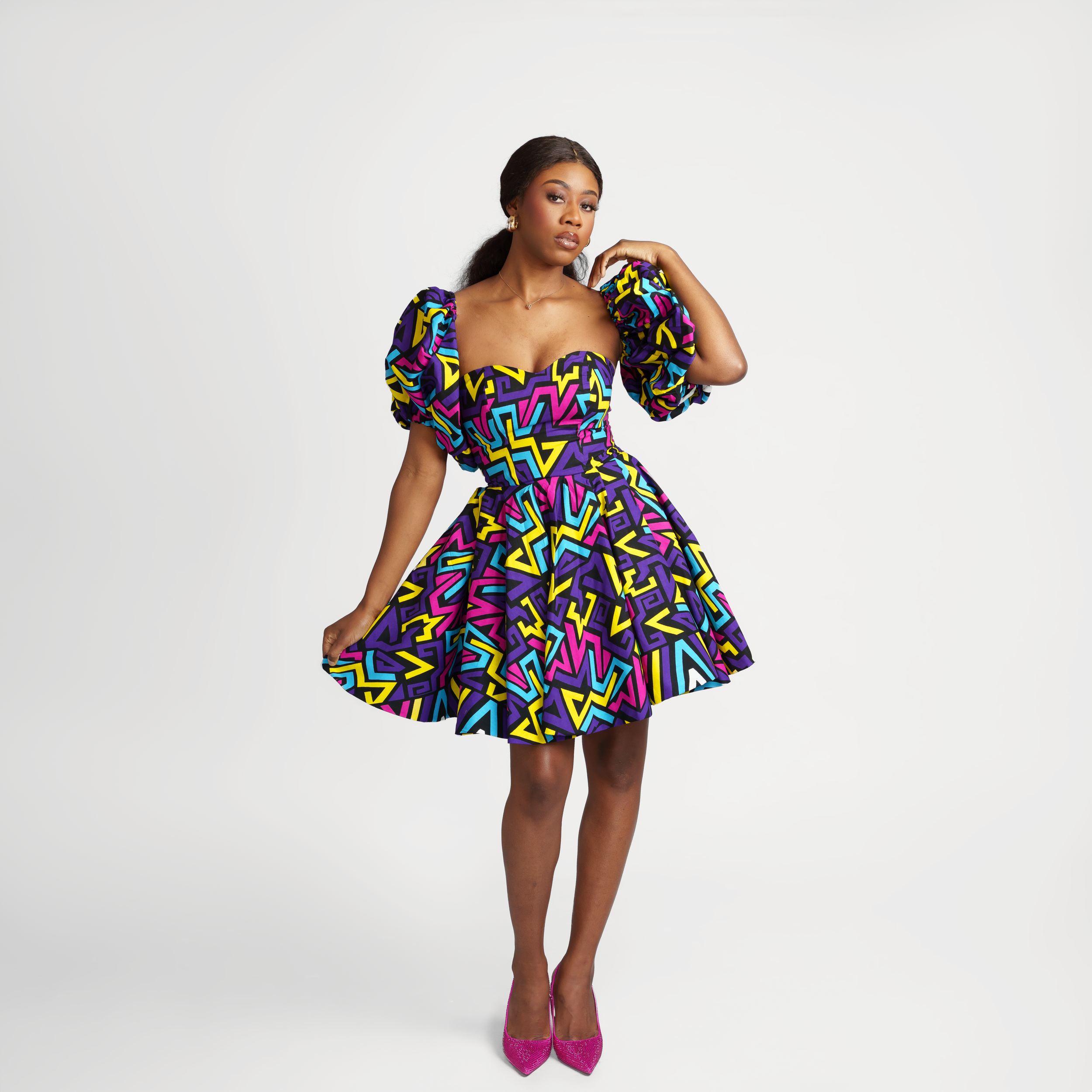 A vibrant African print mini dress with puff sleeves and multicolored geometric patterns.