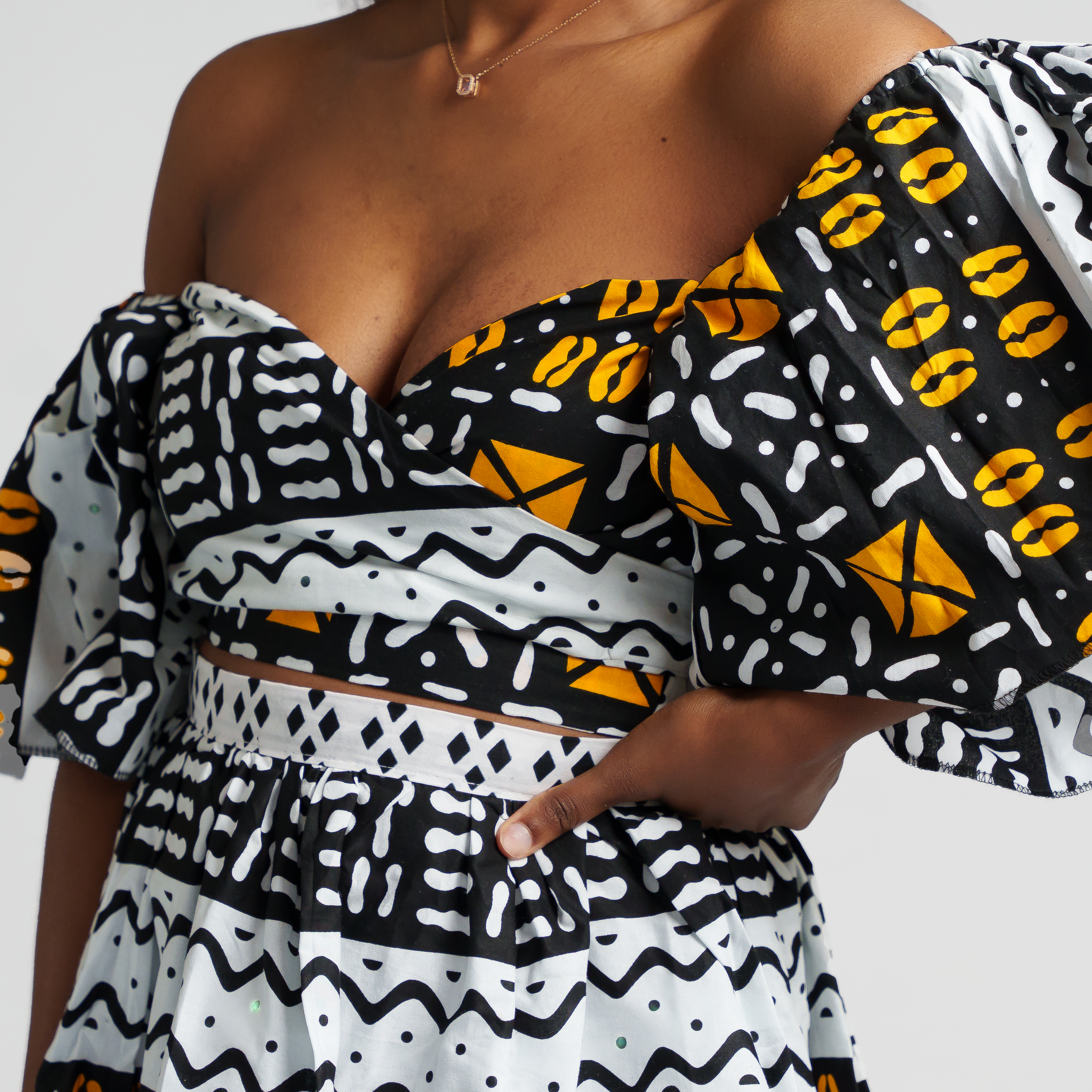 Close-up of African print dress bodice featuring black, white and yellow geometric patterns.