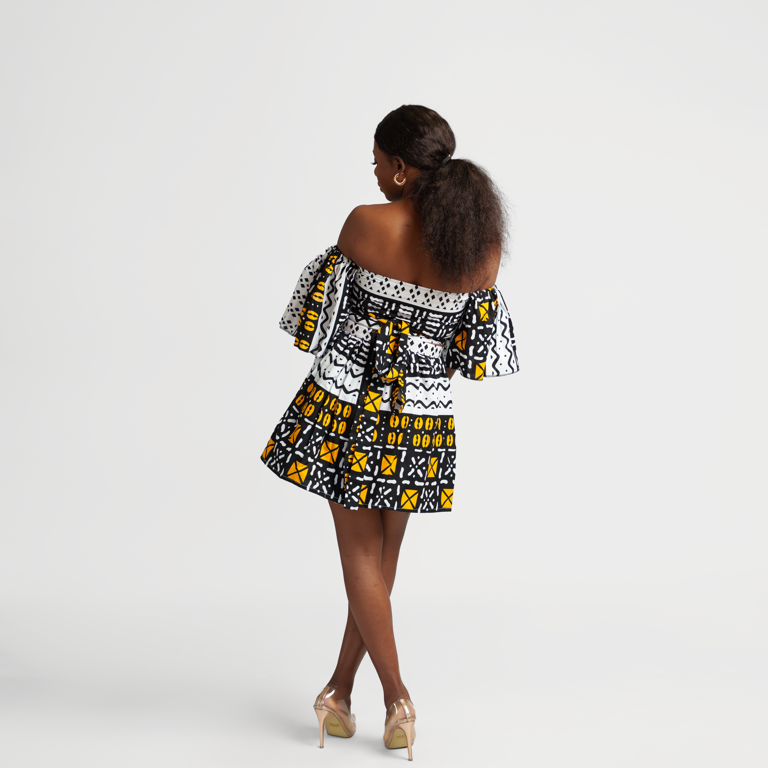 Back view of an off-shoulder African print dress with geometric patterns in black and yellow.