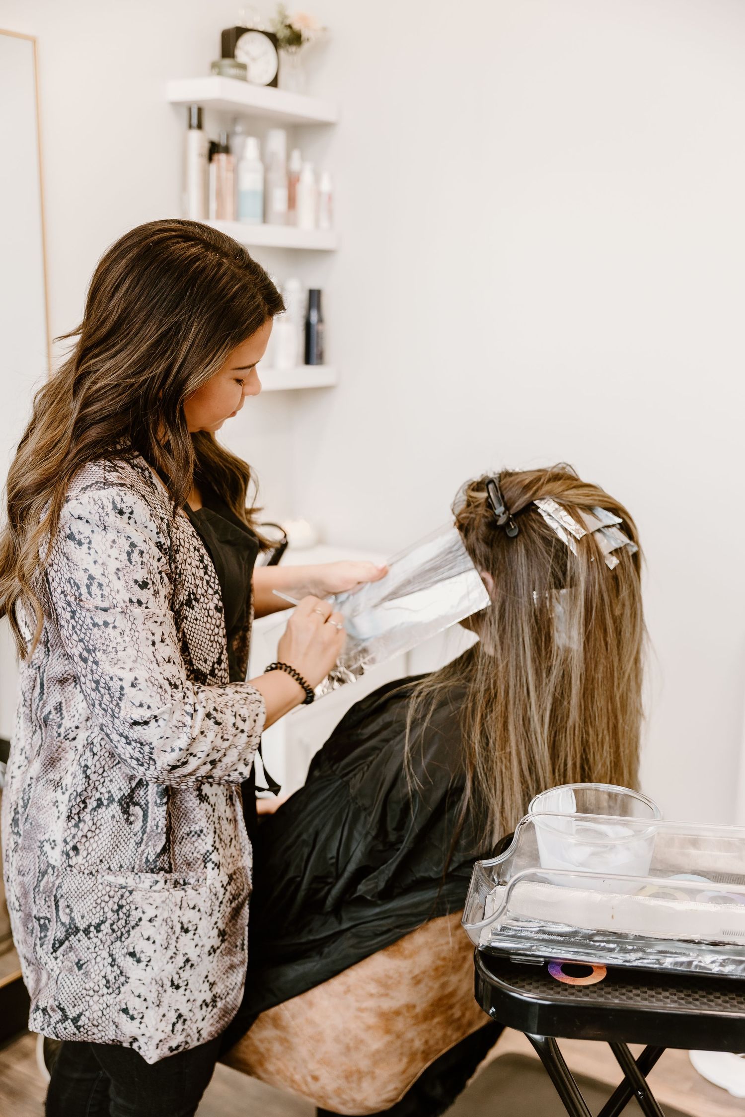 A hairstylist applying foils during a hair coloring service in a salon.