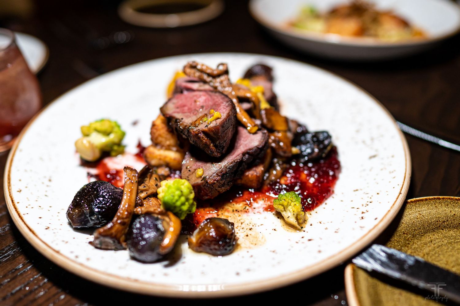 Elegantly plated gourmet dish with colorful garnishes on white ceramic plate.