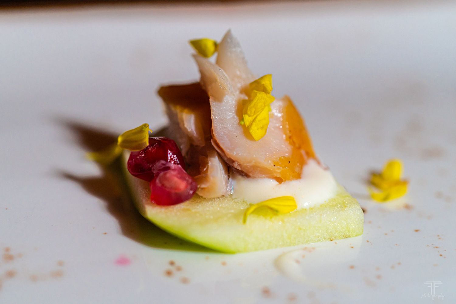 Close-up of elegantly plated gourmet appetizers with colorful garnishes on white plates.