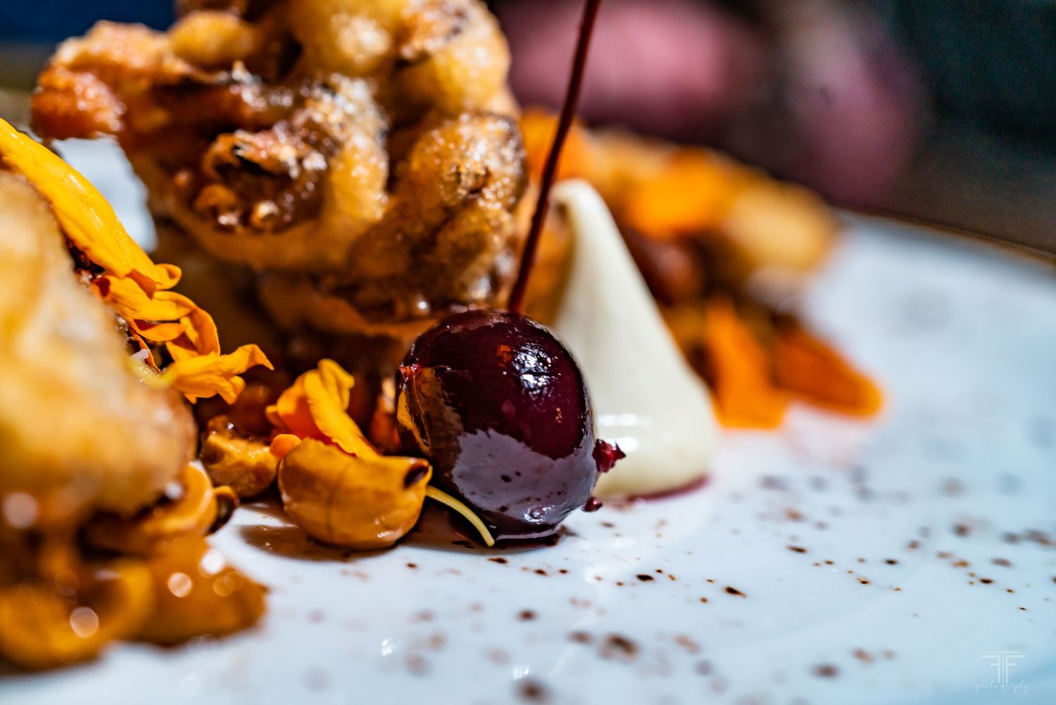 Artfully arranged seafood dish with crispy garnishes and sauce on white plate.