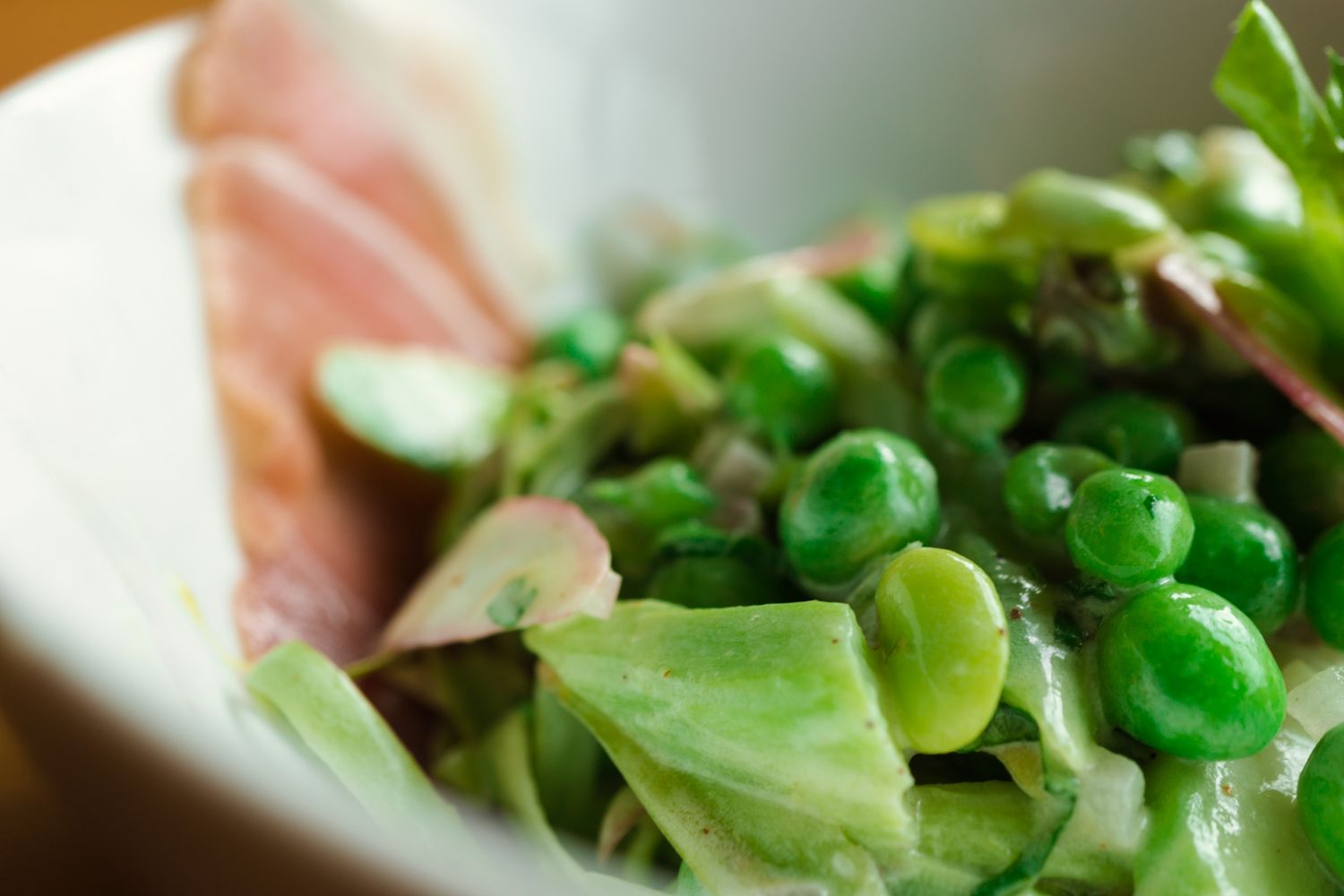 Fresh green salad ingredients arranged on wooden cutting board.