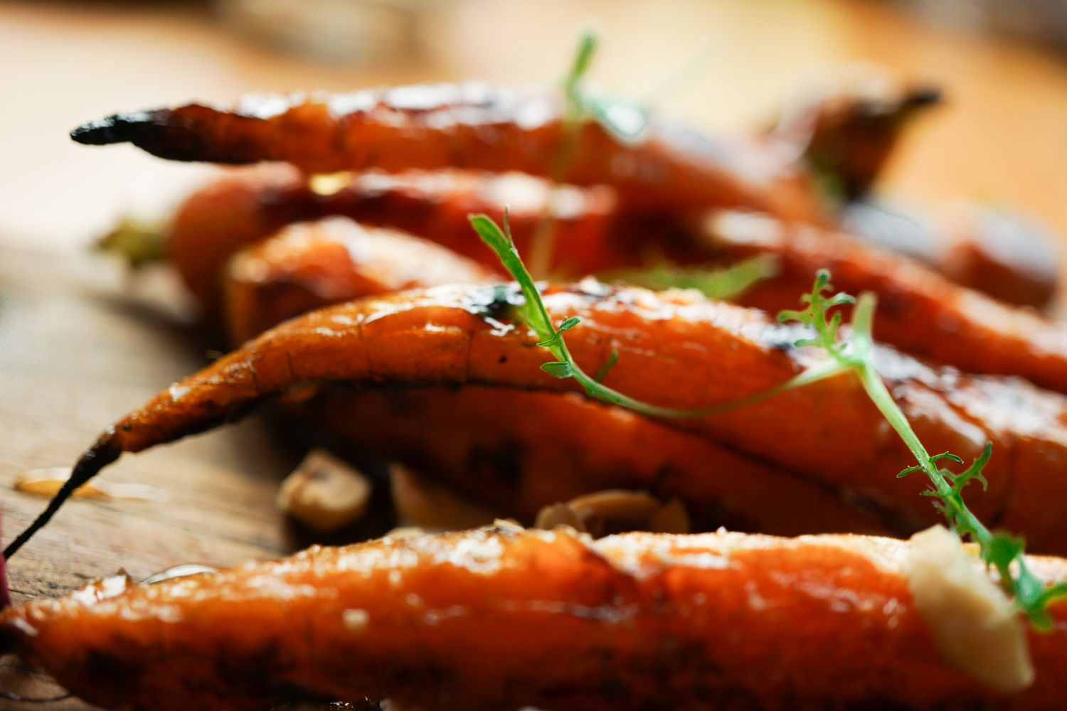 Glazed carrots garnished with fresh herbs on rustic wooden surface.