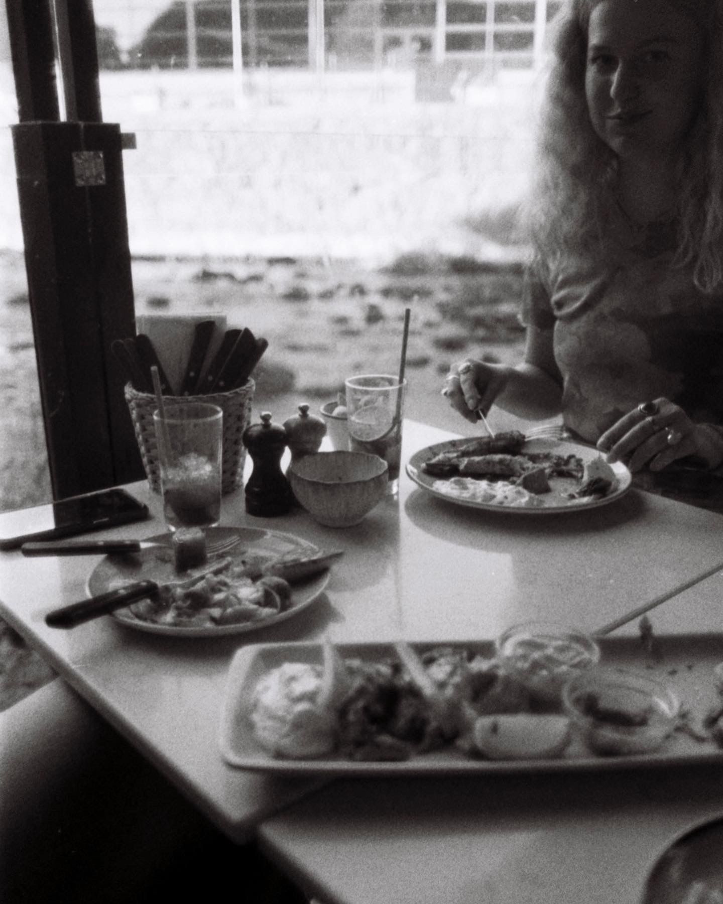 A table set with plates of food and drinks in a black and white photograph.