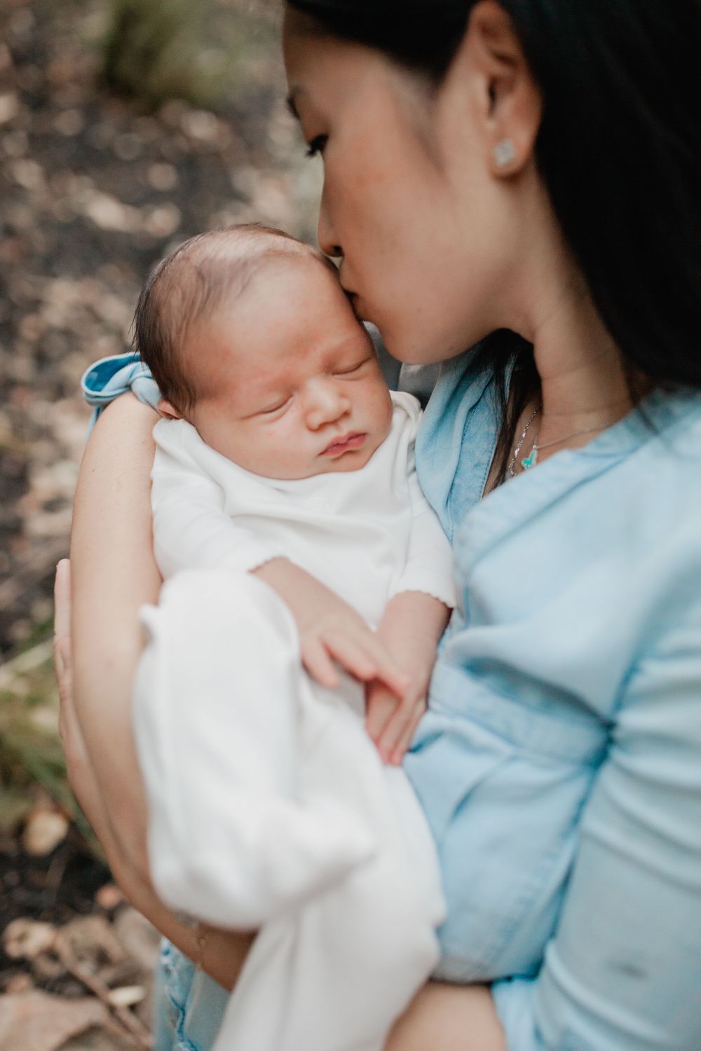 Tender moment between caregiver and sleeping newborn baby in soft lighting.