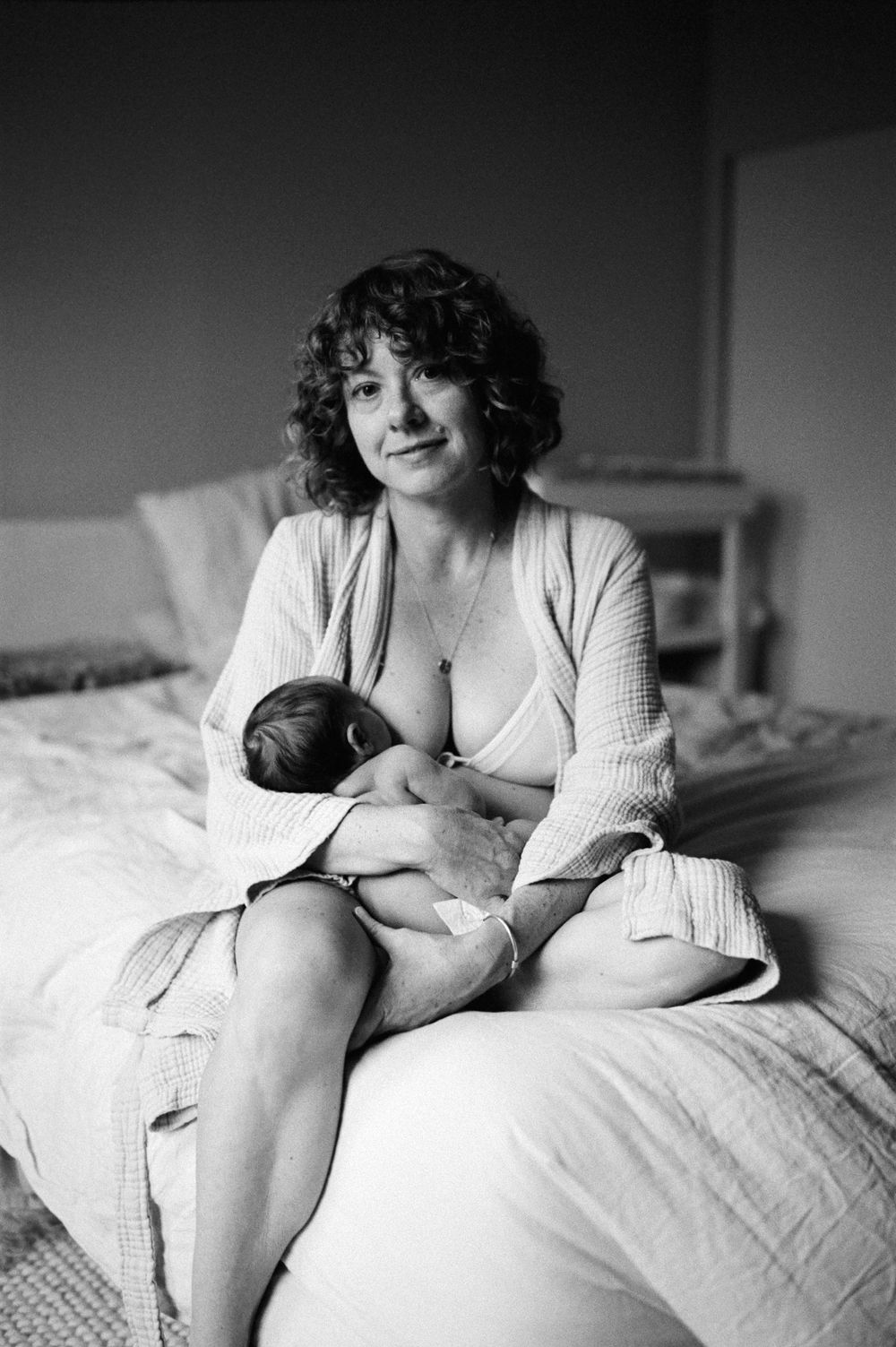 Intimate black and white photography session on a bed with soft natural lighting.