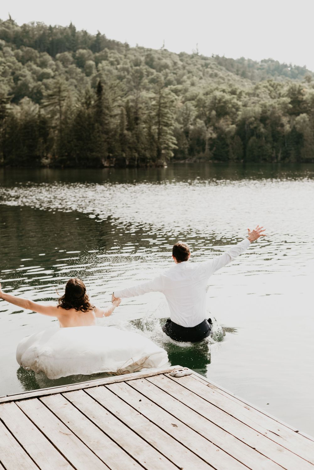 couple on their wedding day jumping into lake