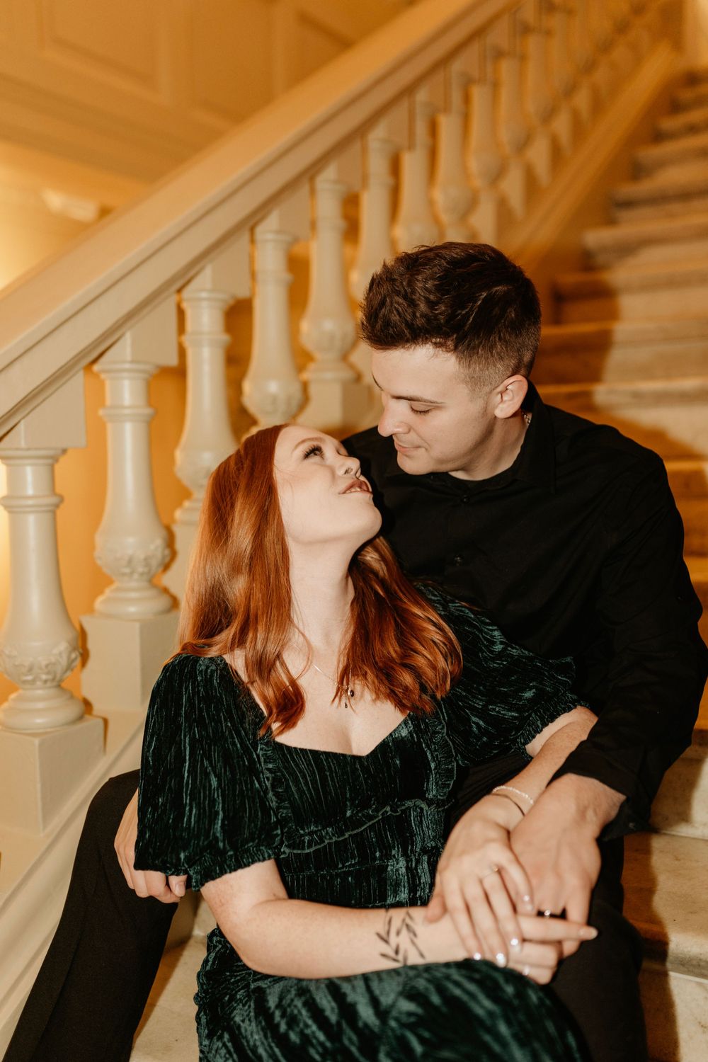 An intimate portrait on ornate stairs with warm lighting and classic architecture.