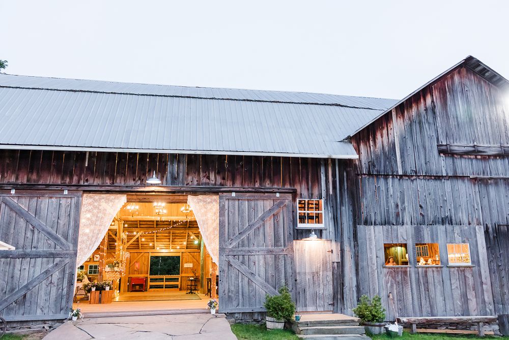 Rustic barn wedding venue exterior with glowing entrance at dusk.