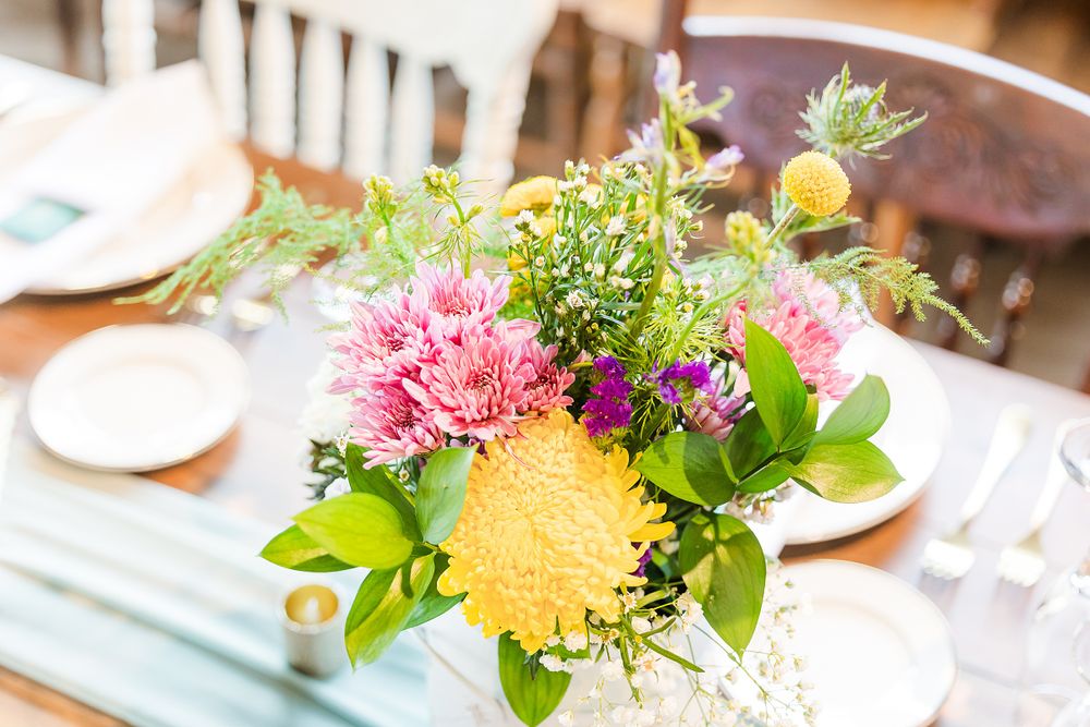 Vibrant wedding centerpiece featuring pink and yellow flowers with lush greenery.
