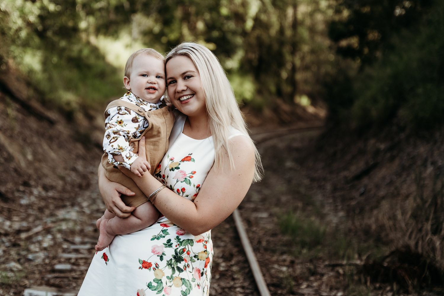 A sweet candid moment between parent and baby wearing matching floral patterns outdoors.