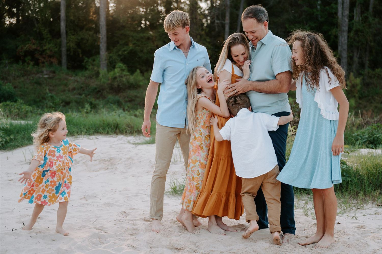 Candid moment of family playing and laughing together on sandy beach path.