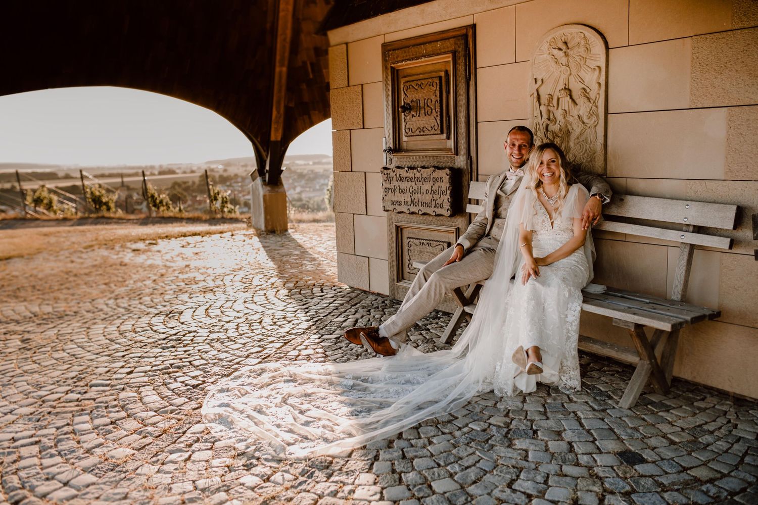 Three people sharing a joyful moment during outdoor wedding celebrations.
