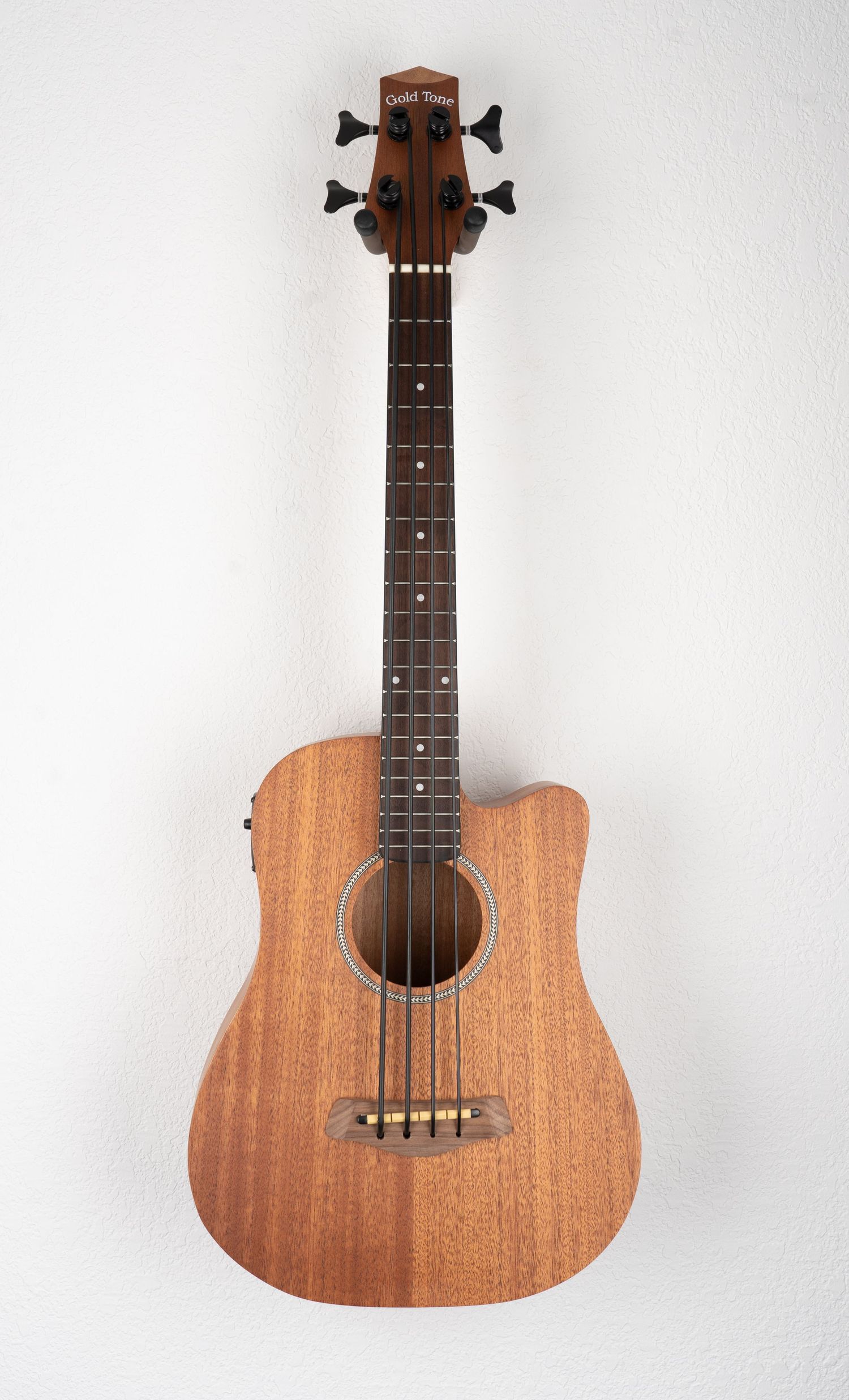 Acoustic bass ukulele with natural wood finish against white background.