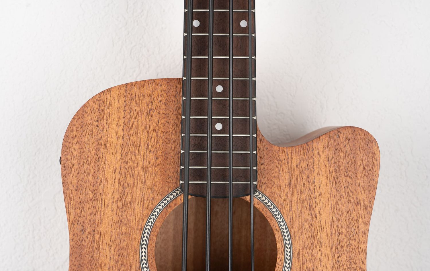Close-up of acoustic bass guitar neck and sound hole showing fretboard and strings.