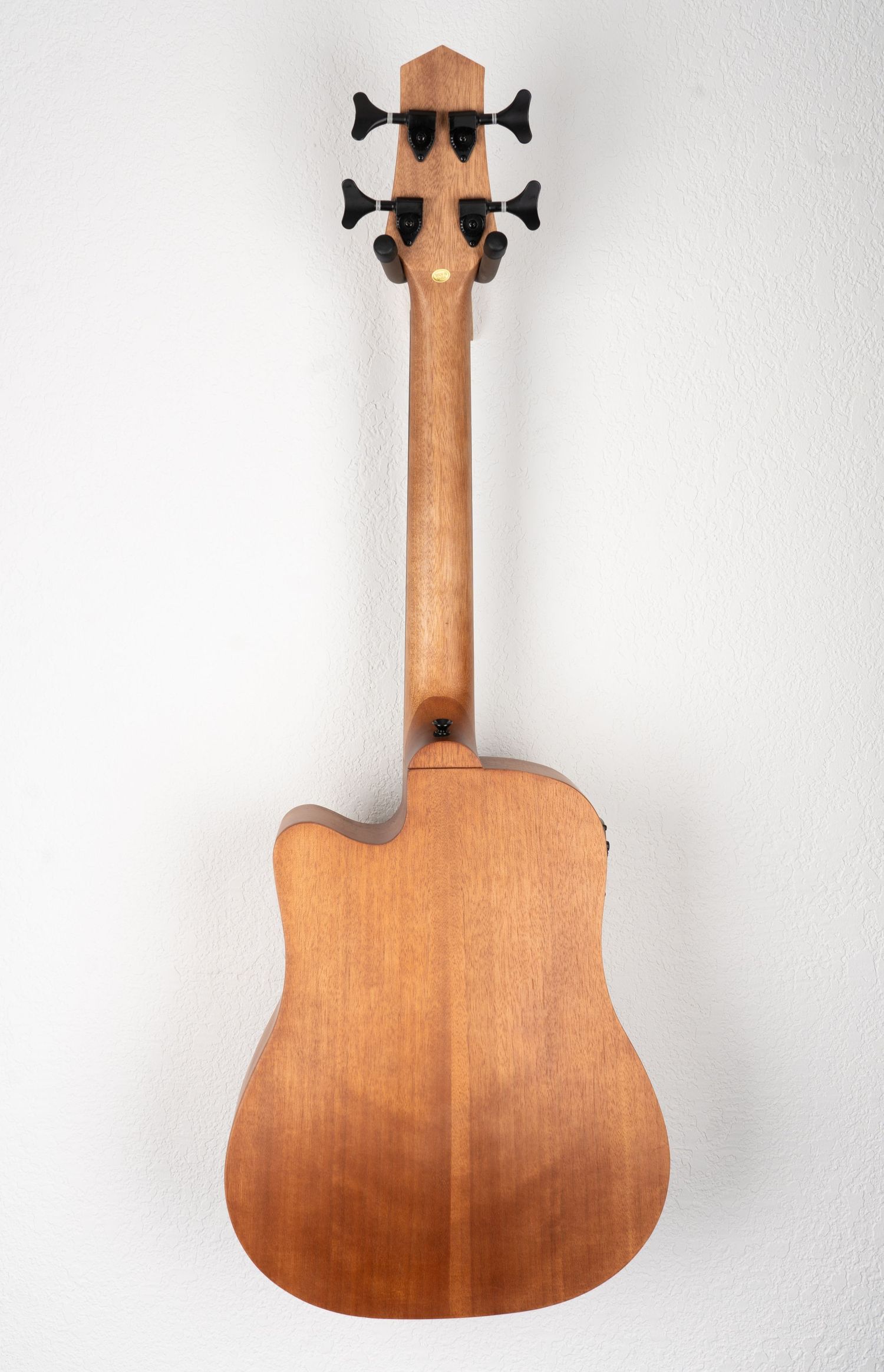 Back view of acoustic bass guitar showing natural wood grain finish and curved body shape.