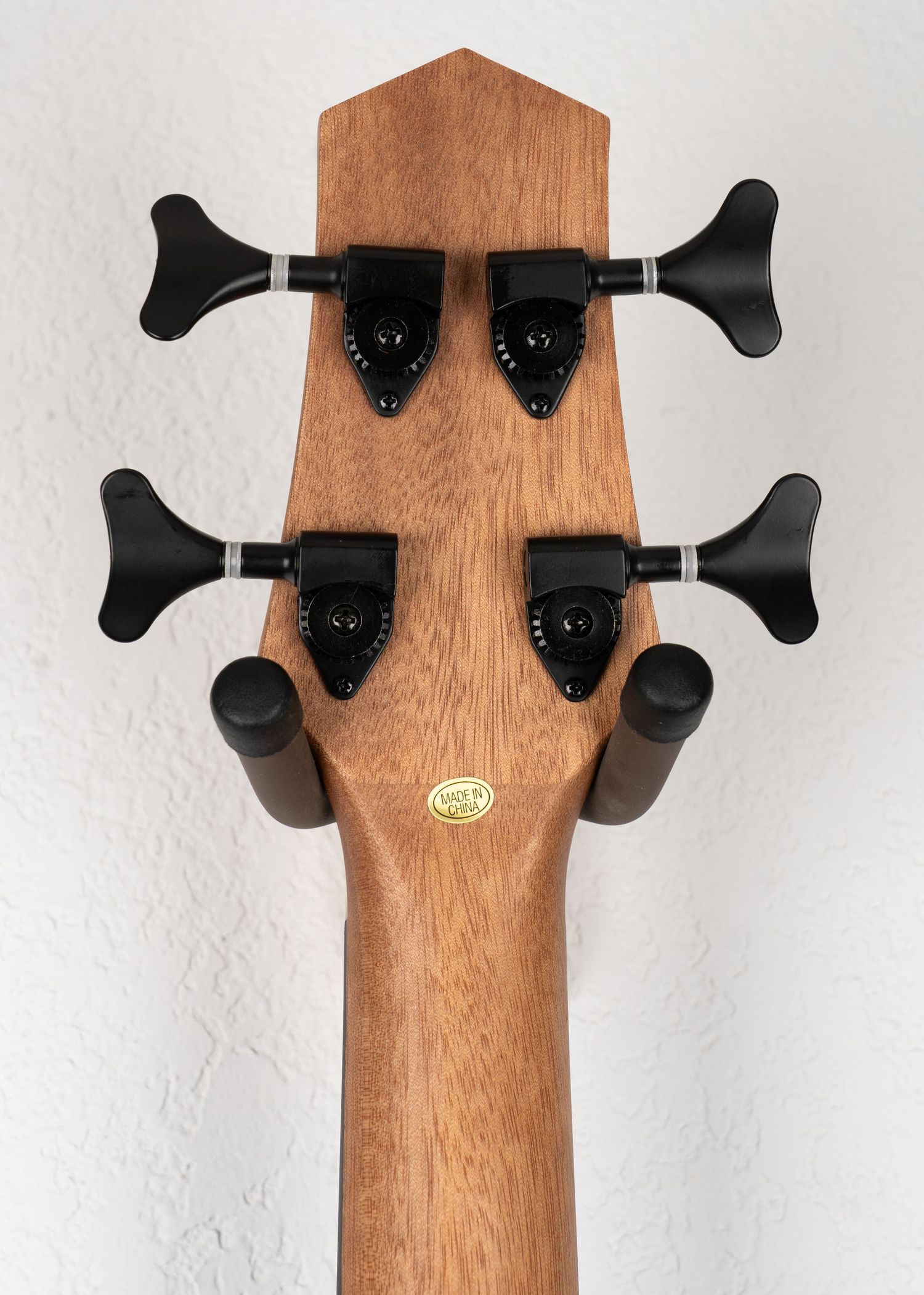Headstock detail showing black tuning machines and Gold Tone logo on acoustic bass guitar.