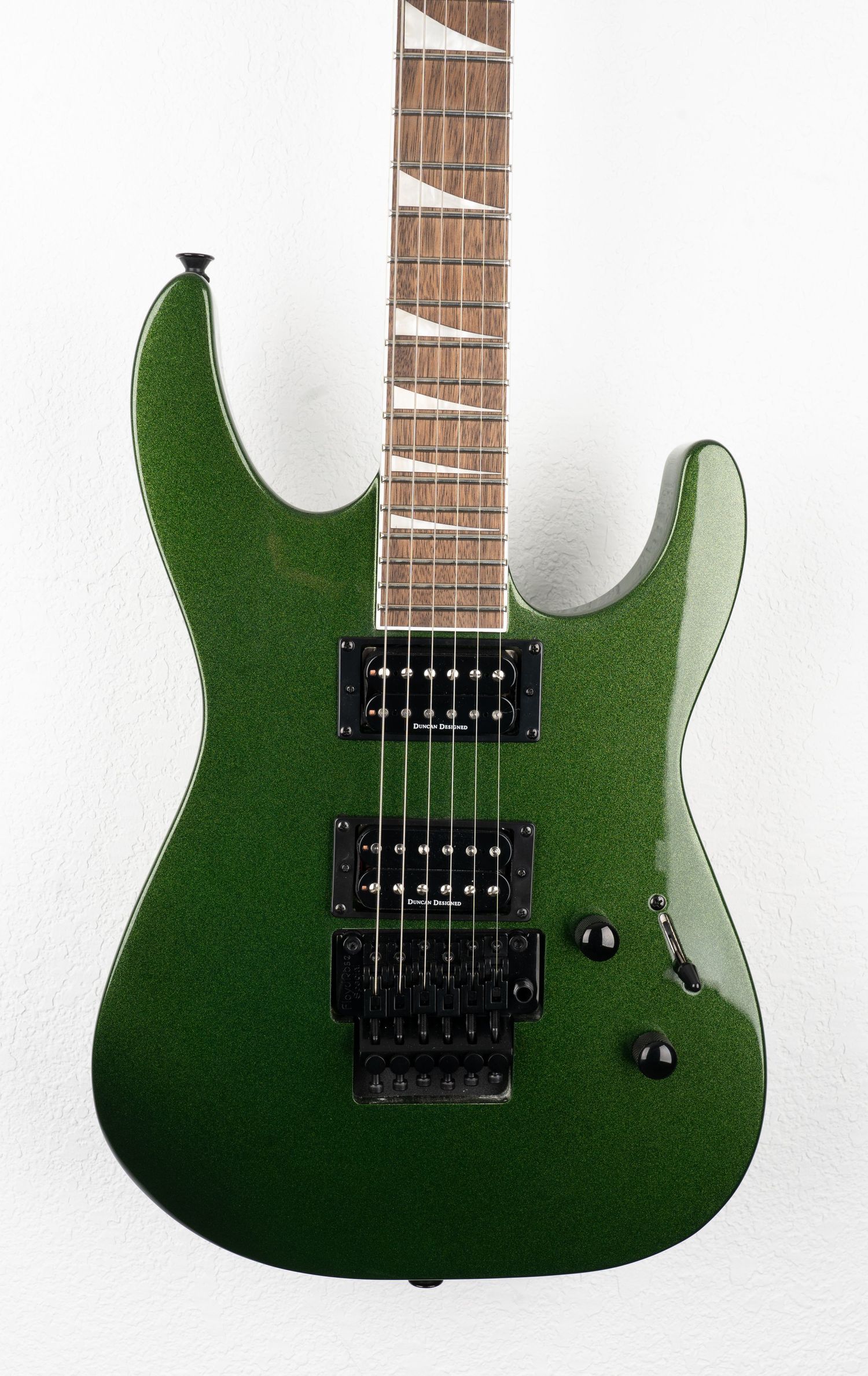 Green metallic electric guitar body with dual humbuckers and rosewood fretboard against white background.