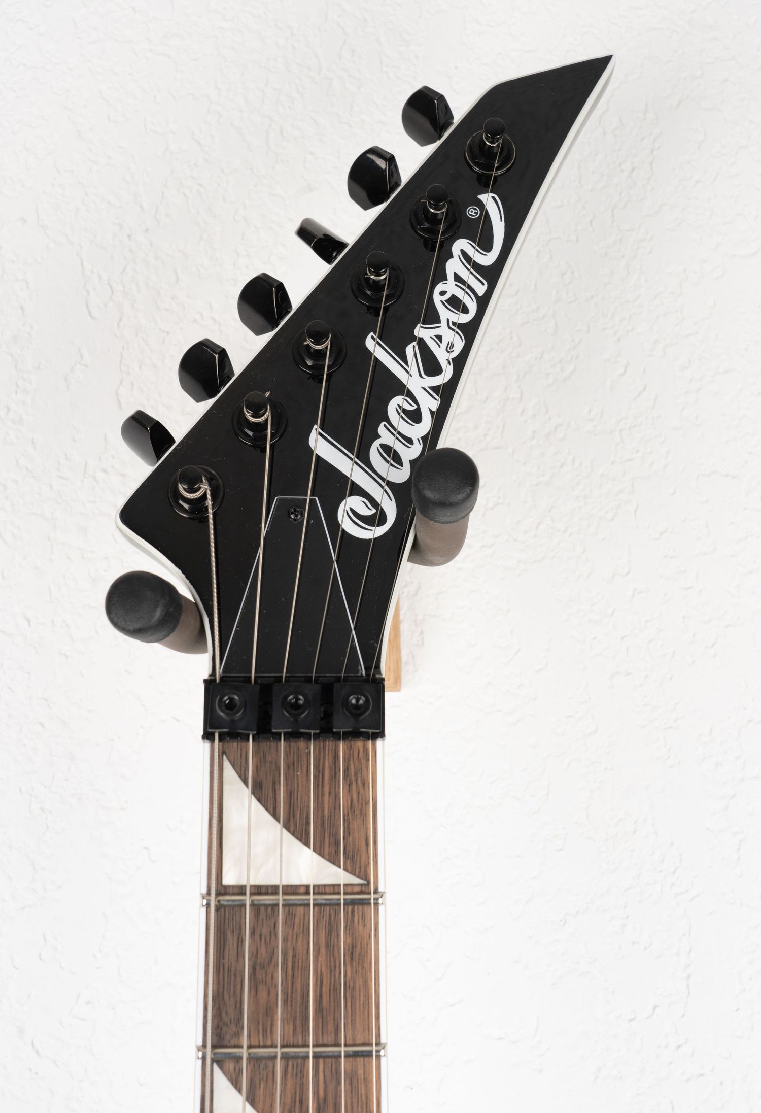 Jackson guitar headstock with black tuners and logo against white background.