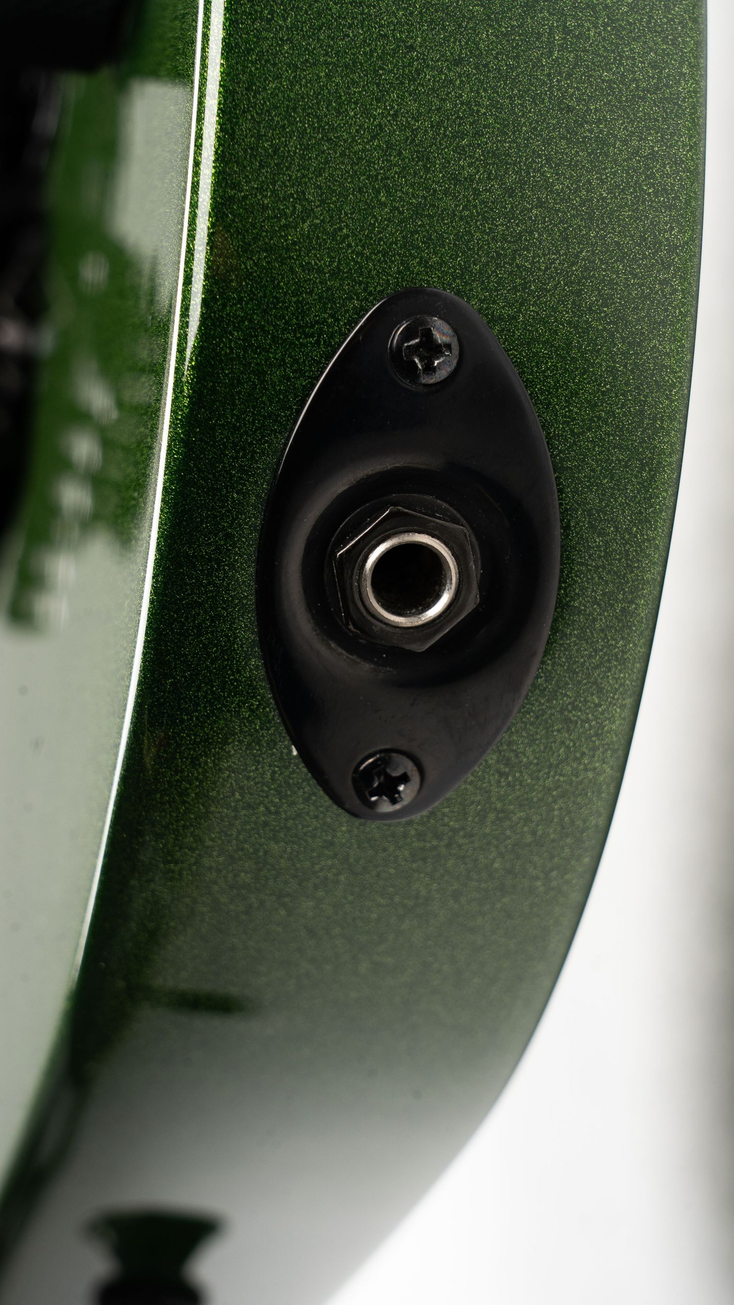 Close up of guitar output jack mounted on green metallic body.